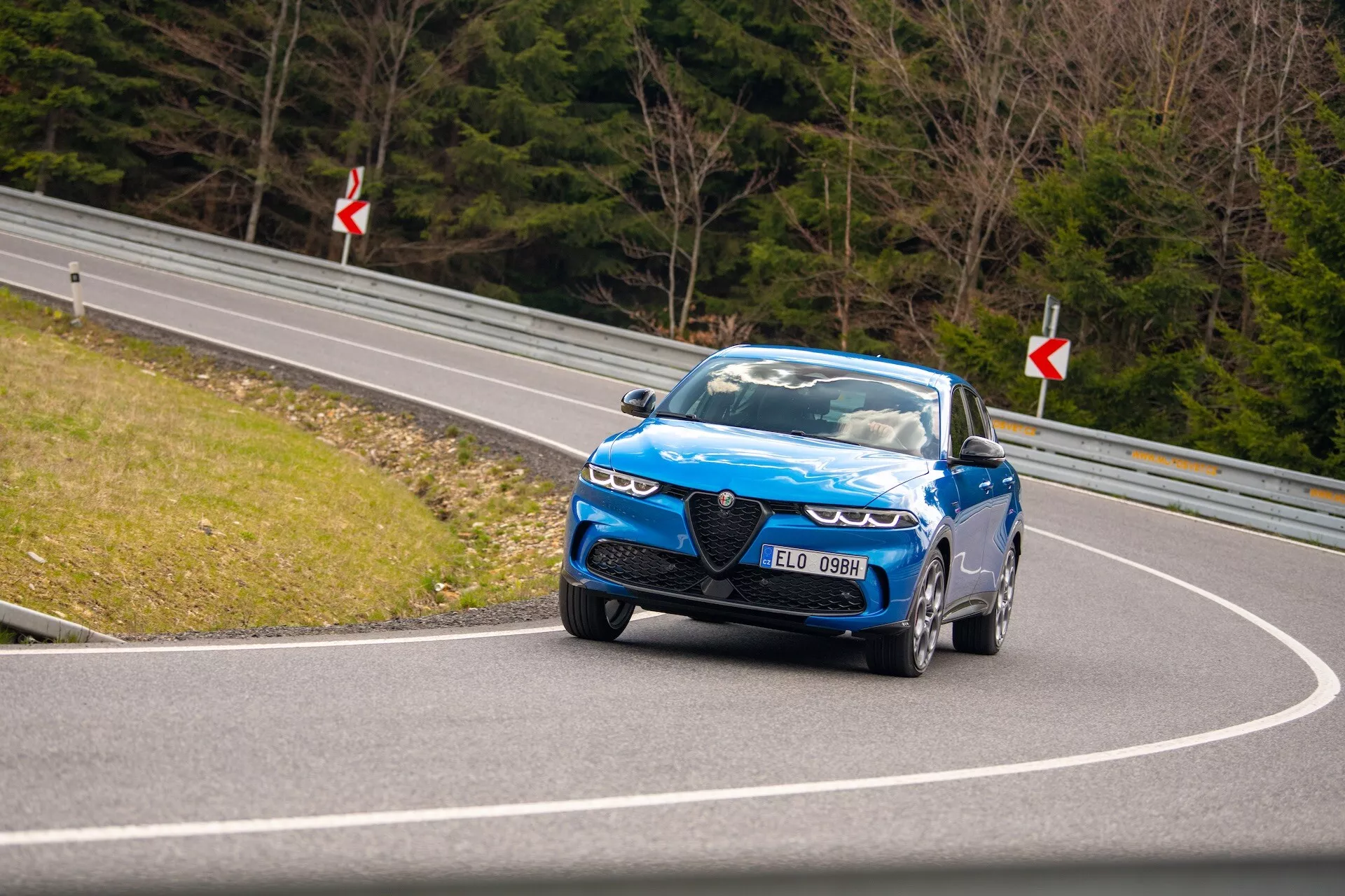Condução dinâmica do Alfa Romeo Tonale 2022 em estrada curva exibindo visão do quarto frontal, faróis LED, grade distintiva e rodas de alto desempenho