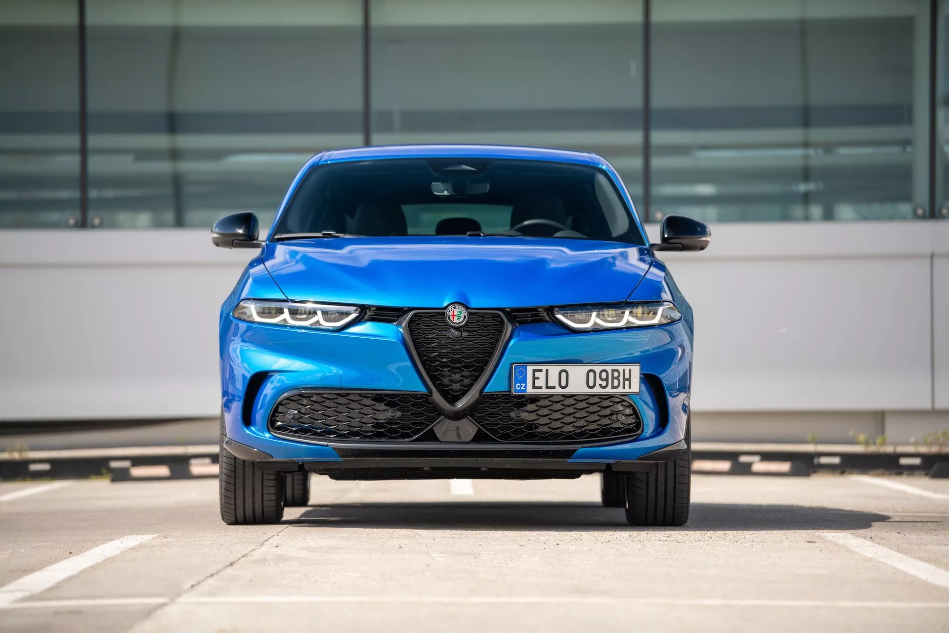 Alfa Romeo Tonale 2022 azul, vista frontal em estacionamento destacando grade com emblema, faróis de LED e características de design aerodinâmico