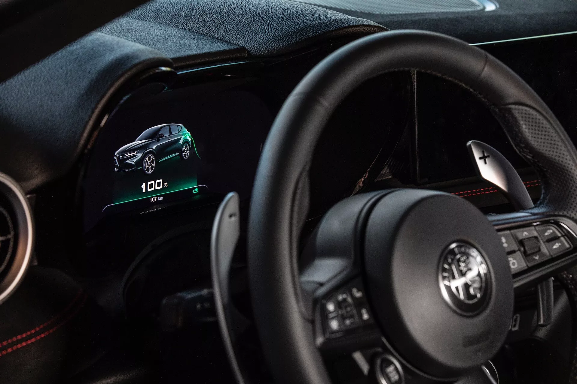 Interior do Alfa Romeo Tonale 2022 mostrando a perspectiva do condutor com painel digital, volante multifuncional e indicadores de veículo elétrico