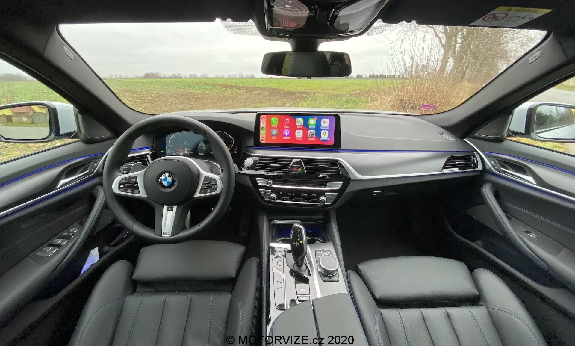 Vista frontal de um BMW 520i Touring Steptronic 2020 com acabamento metálico elegante, exibindo seu design elegante, faróis de LED avançados e a icônica grade de rim em um ambiente urbano moderno.