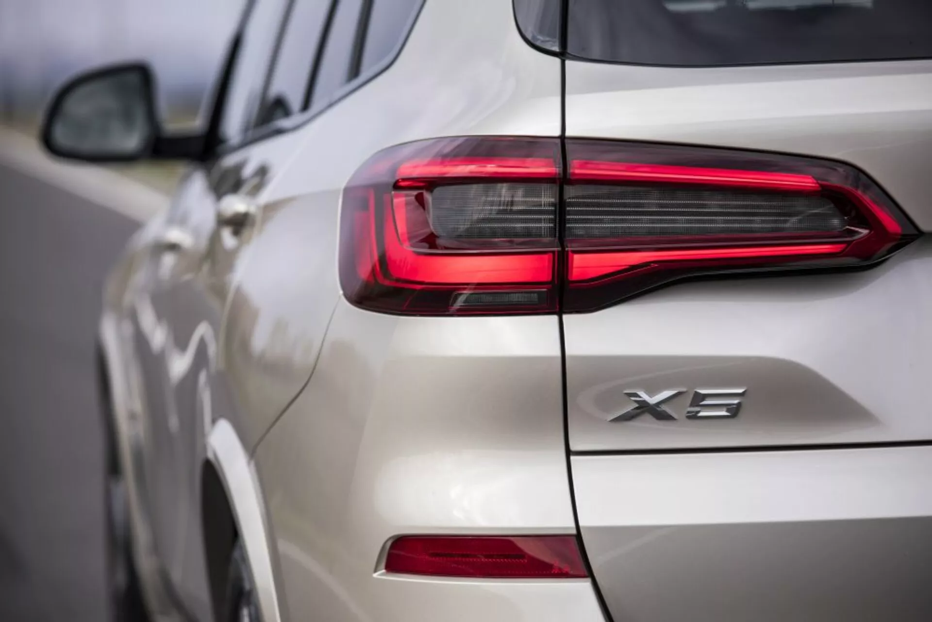 Vista de perto da traseira de um BMW X3 2018 branco, exibindo o design da luz traseira LED e o emblema X3, focando na assinatura de luz horizontal moderna e nos detalhes intricados na tampa do porta-malas e lateral.