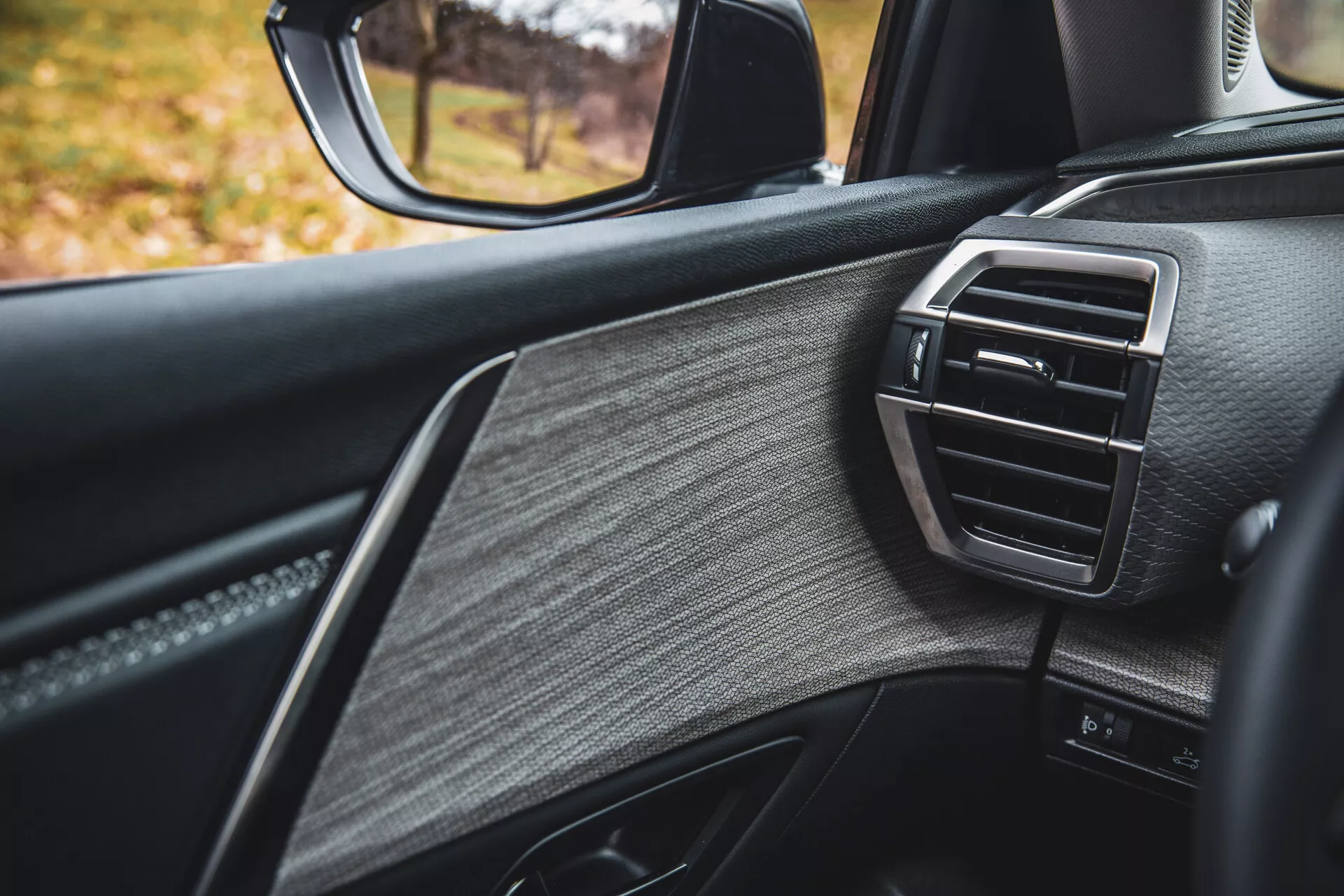 Vista detalhada da porta do lado do passageiro do Citroen C5-X 2022, destacando o design de luxo com couro texturizado, acabamento brilhante e saída de ar do controle climático