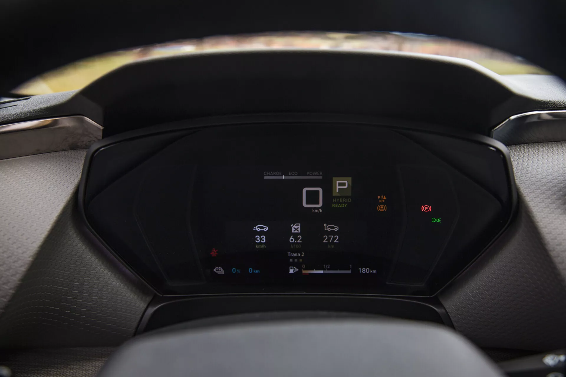 Visão aproximada do painel digital de um Citroen C5-X 2022 exibindo métricas do veículo, incluindo indicador de marcha, velocímetro e consumo de energia, com volante e pára-brisa desfocados em primeiro plano e fundo respectivamente.
