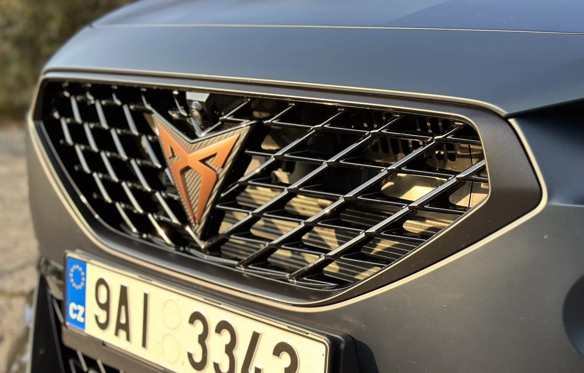 Visão detalhada da grade frontal e do para-choque do Cupra Formentor 2020 mostrando o emblema, barras horizontais e um acabamento metálico, enfatizando seu design automotivo e marca