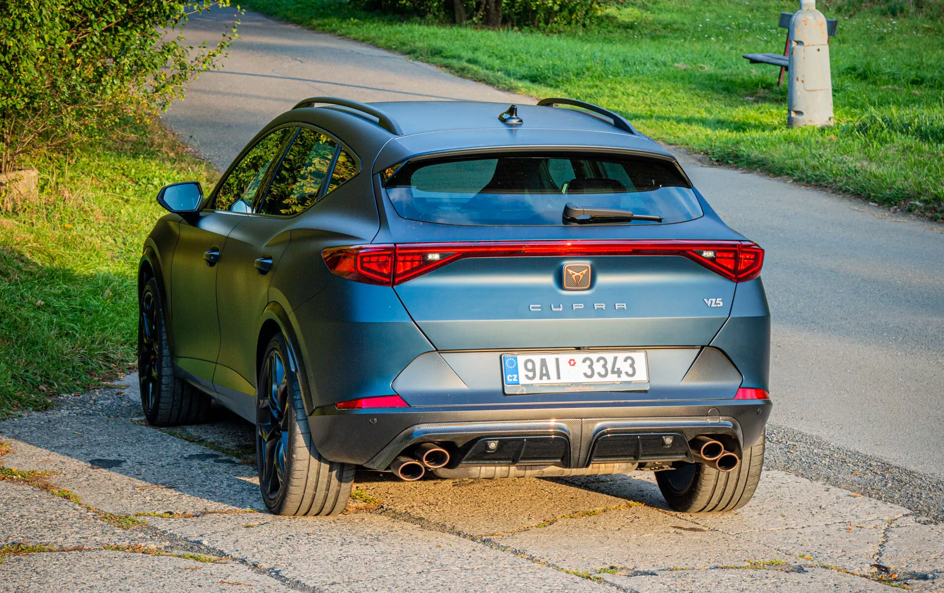 Vista traseira de um SUV Cupra Formentor VZ5 2020 com luzes traseiras LED, sistema de escape quádruplo, difusor e para-choque traseiro esportivo, rodas de múltiplos raios e acabamento mate antracite, fotografado em um cenário suburbano durante o dia