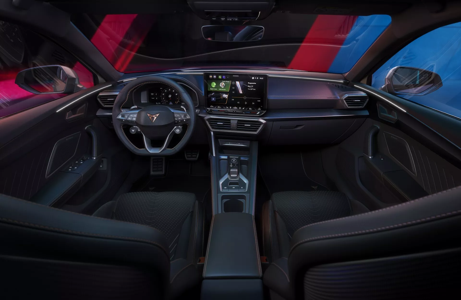 Imagem do interior do Cupra Leon 2024 (face-lift da primeira geração) a partir da perspectiva do banco traseiro, mostrando o painel elegante e minimalista com um grande ecrã táctil, o volante moderno de dois raios com controlos do veículo e a consola central estreita com acabamento que imita madeira. Os bancos dianteiros desportivos, a iluminação ambiente e o teto panorâmico realçam a atmosfera sofisticada e tecnológica do habitáculo.