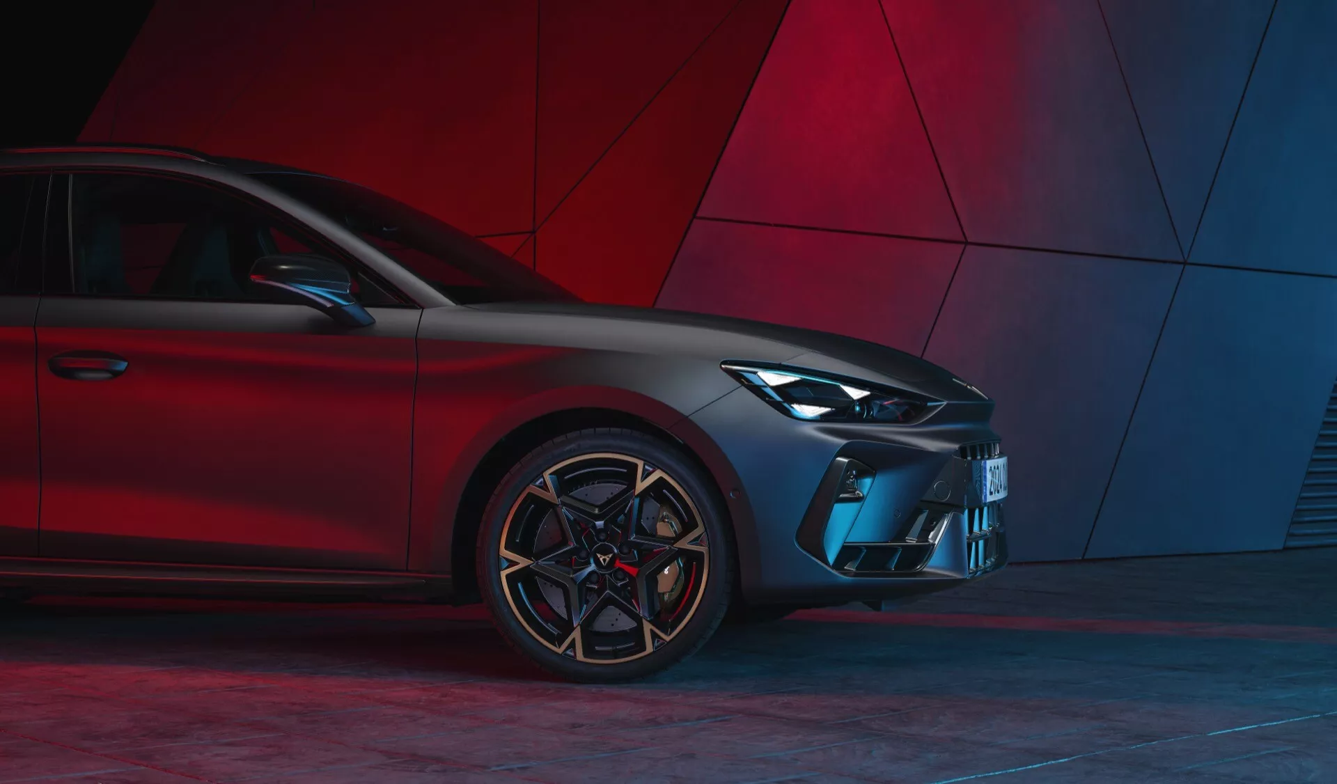 Vista frontal de três quartos do Cupra Leon 2024 (facelift da 1ª geração) destacando o design moderno com faróis de LED, grade esportiva, para-choques esculpido, entradas de ar angulares, rodas de liga leve com vários raios e pneus de perfil baixo contra um fundo abstrato vermelho.