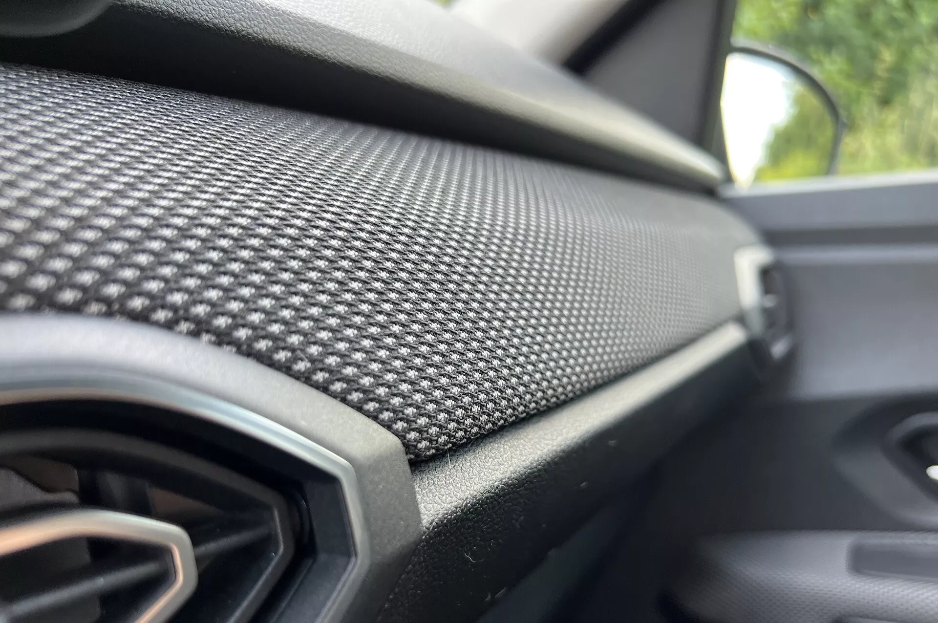Visão detalhada do painel do lado do passageiro do Dacia Jogger 2022 com padrão de fibra de carbono e ventilação, enfatizando o design moderno e acabamento de luxo