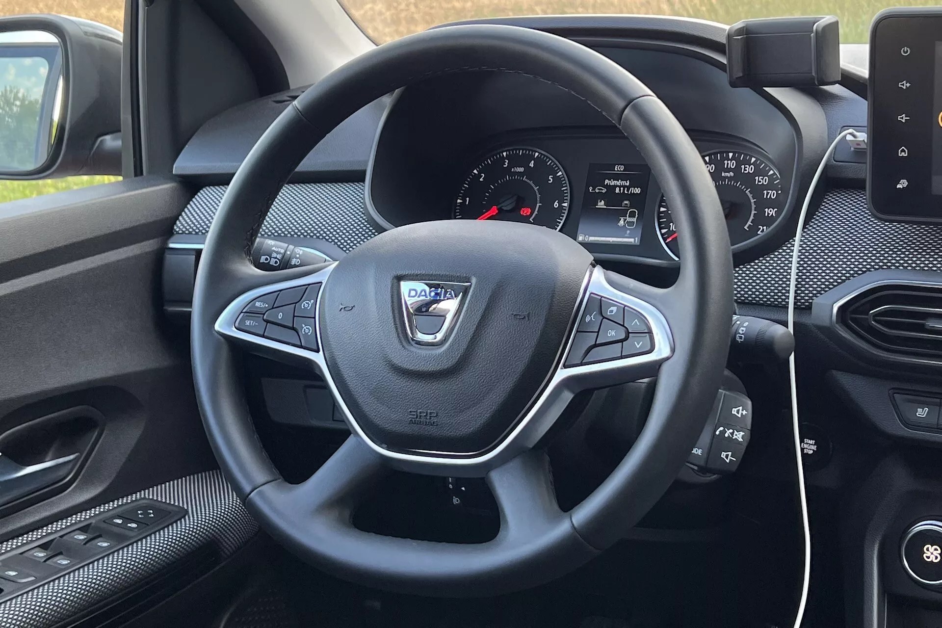 Vista interior do Dacia Jogger 2022 do assento do condutor, focando no volante com controles multifunções e painel com sistema de infotenimento