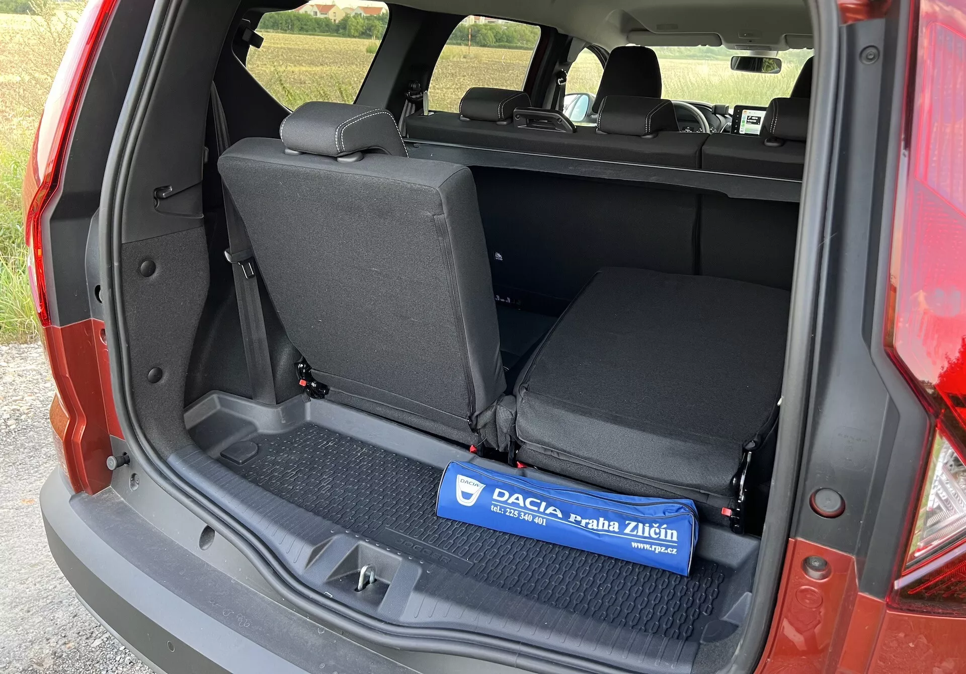 Dacia Jogger 2022 mostrando espaço de carga interior de um ângulo lateral esquerdo com porta-malas aberto, apresentando uma área de carga plana com tapete de borracha, assentos traseiros rebatíveis 60/40, e detalhamento de acabamento lateral sem componentes de tecnologia avançada ou de luxo visíveis