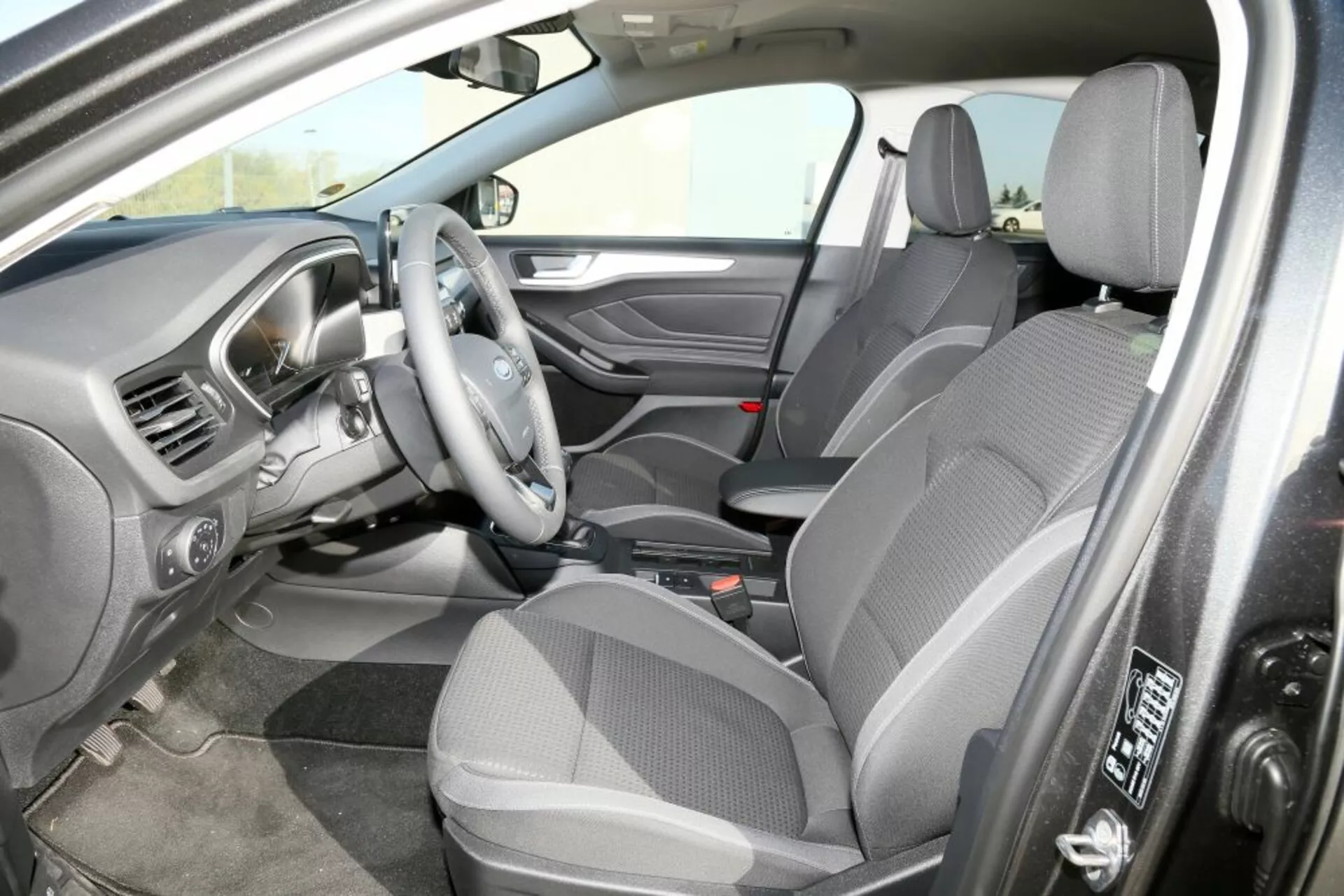 Vista interior do Ford Focus 2013 a partir da perspectiva do passageiro dianteiro mostrando assentos de tecido, layout de direção à direita e o console central com transmissão automática