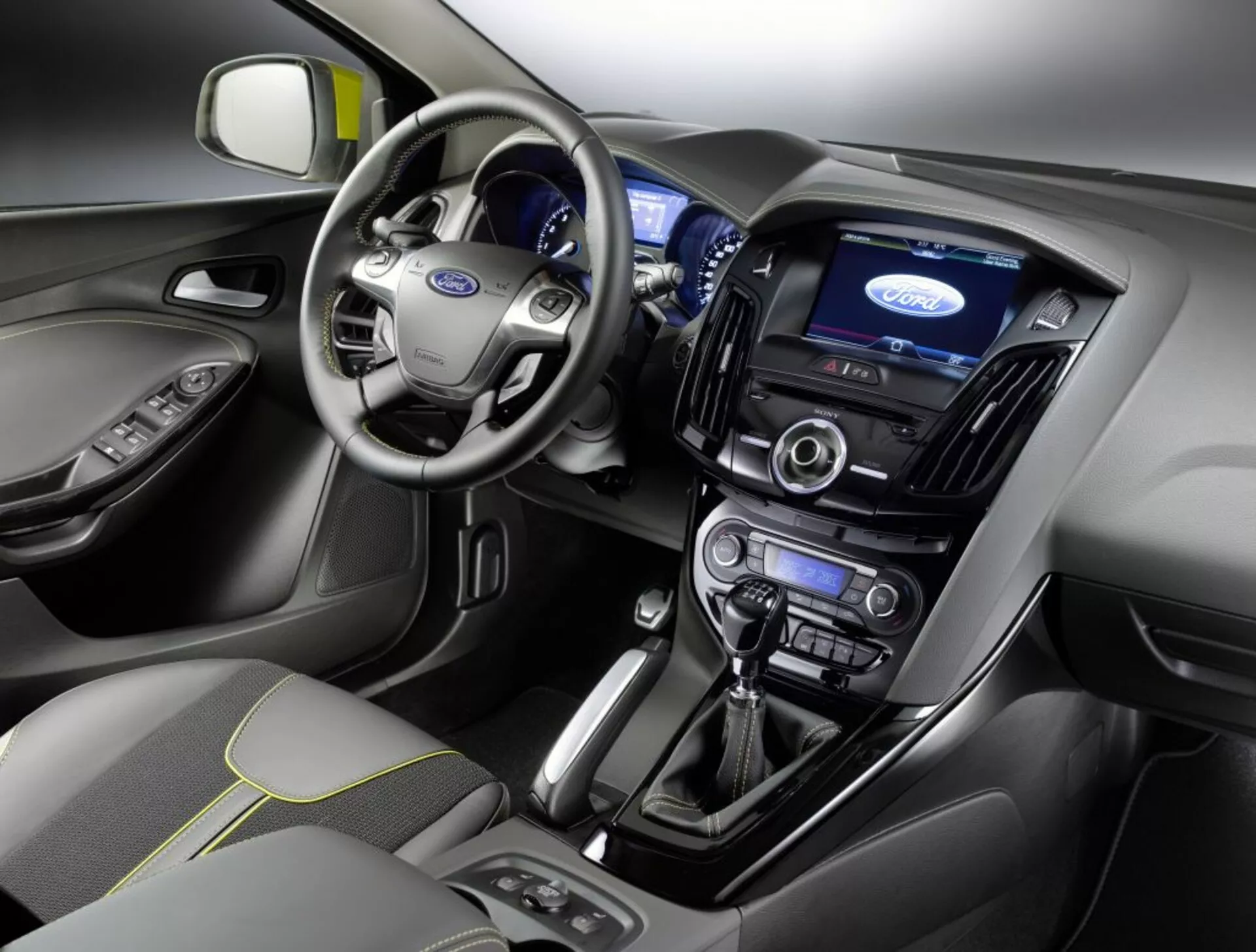 Vista interior de um Ford Focus 2011 apresentando o painel de instrumentos, área do condutor, volante com logotipo da Ford, cluster de instrumentos iluminado, tela de toque central do sistema de infotenimento, controles de clima, sistema de áudio, alavanca de câmbio automática e banco do passageiro da frente com cobertura de tecido e padrão de costura
