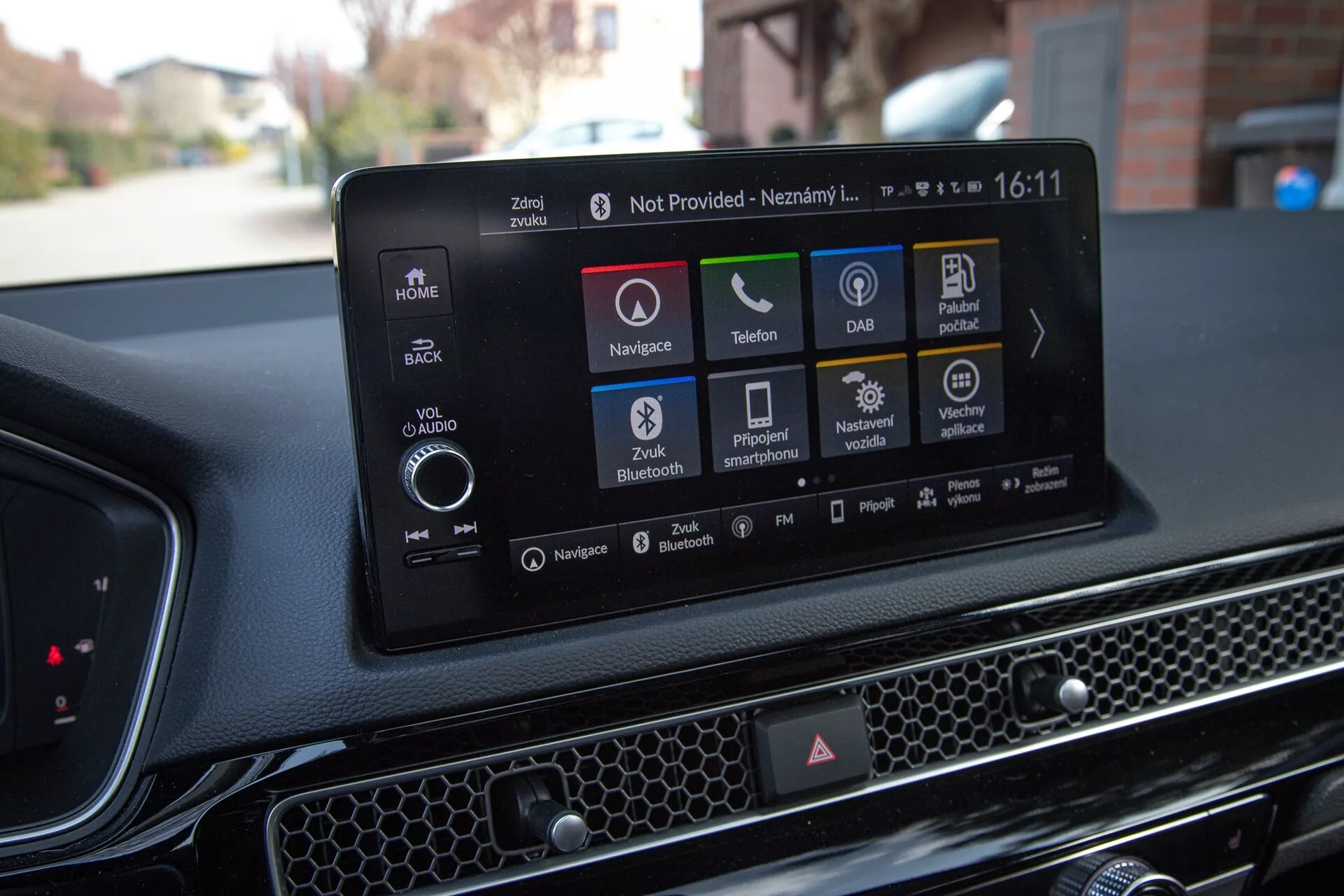 Interior do Honda Civic 2022 mostrando o moderno sistema de infotainment touchscreen com navegação, ícones de reprodução de áudio e mídia, conectividade de telefone, DAB, status do carro, opções de Bluetooth e configurações do veículo, contra um painel texturizado com padrão de colmeia.