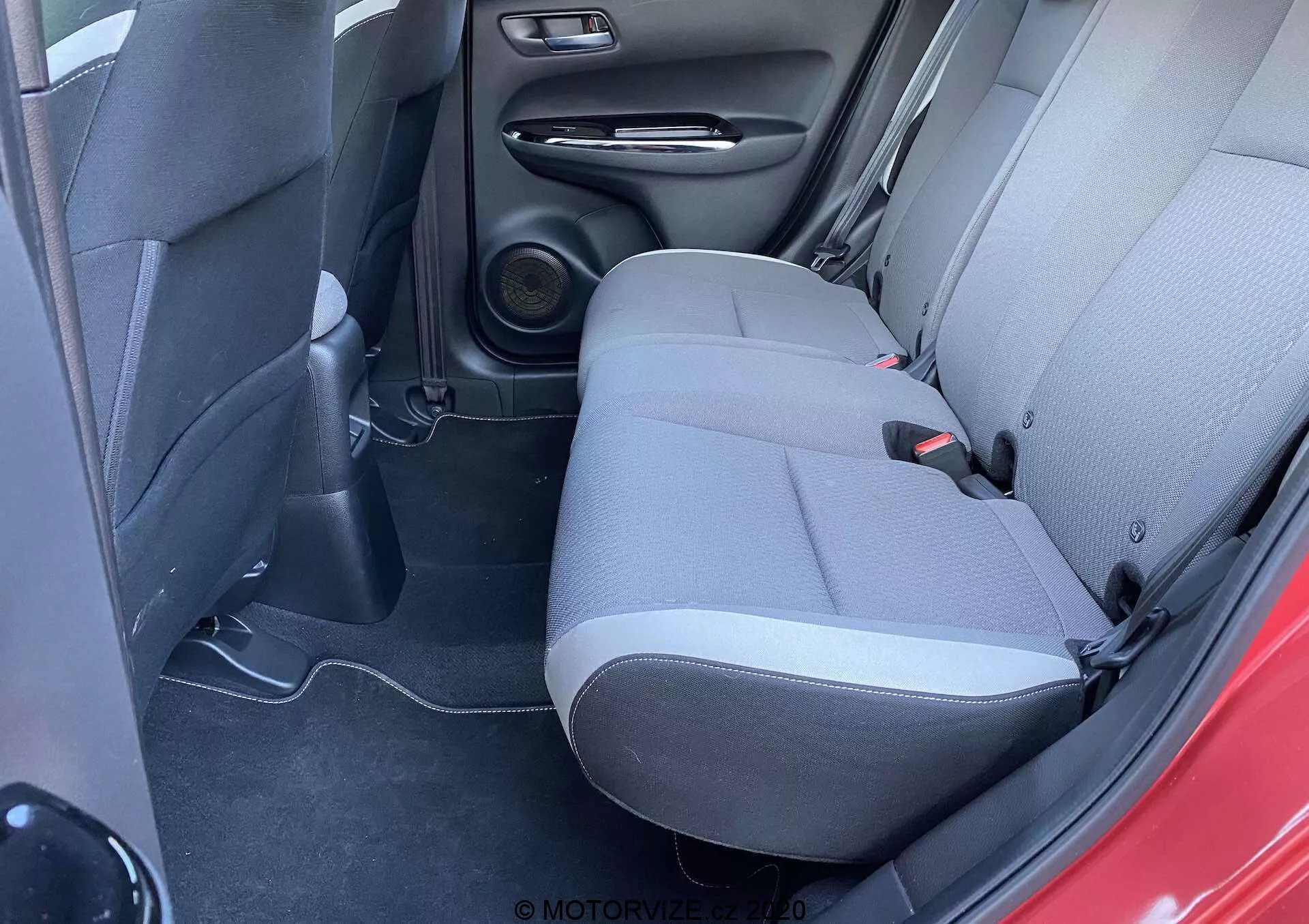 Vista interior do Honda Jazz 2020 (Jazz-Crosstar), mostrando a área dos assentos traseiros de um ângulo ligeiramente elevado, destacando a estofaria em tecido de duas tonalidades, o sistema de alto-falantes e os elementos de design práticos.
