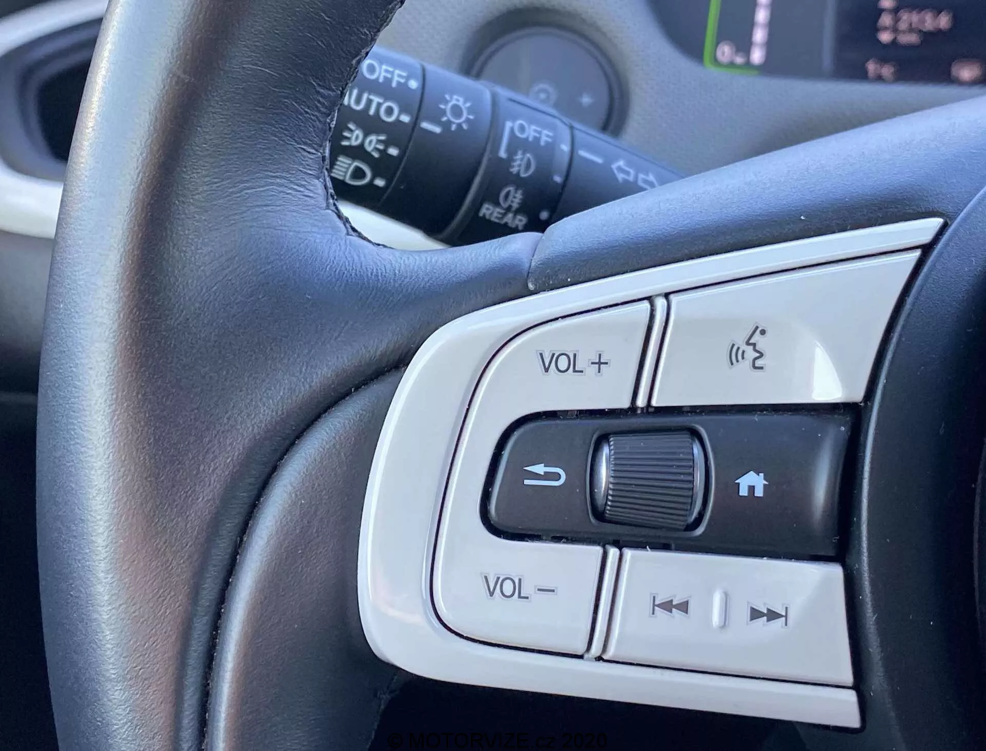 Vista aproximada dos controles montados no volante do Honda Jazz Crosstar 2020, mostrando ajuste de volume, sistema de telefone com mãos livres e botões possíveis para controle de cruzeiro ou seleção de faixas de áudio. Foco central no volante revestido em couro com adornos prateados que ressaltam o conforto e o design elegante.