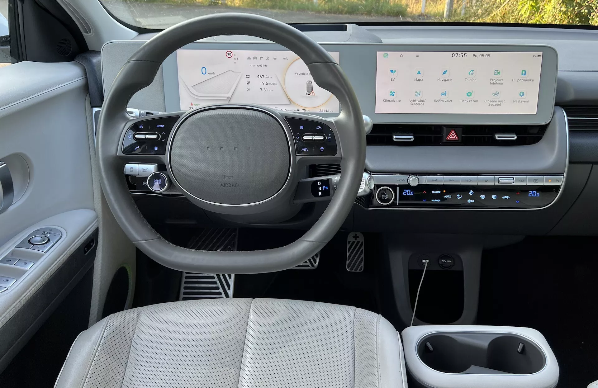 Visão do interior do Hyundai IONIQ 5 2021 mostrando o painel do lado do motorista, cluster de instrumentos digital e sistema de infotainment central a partir da perspectiva do passageiro traseiro