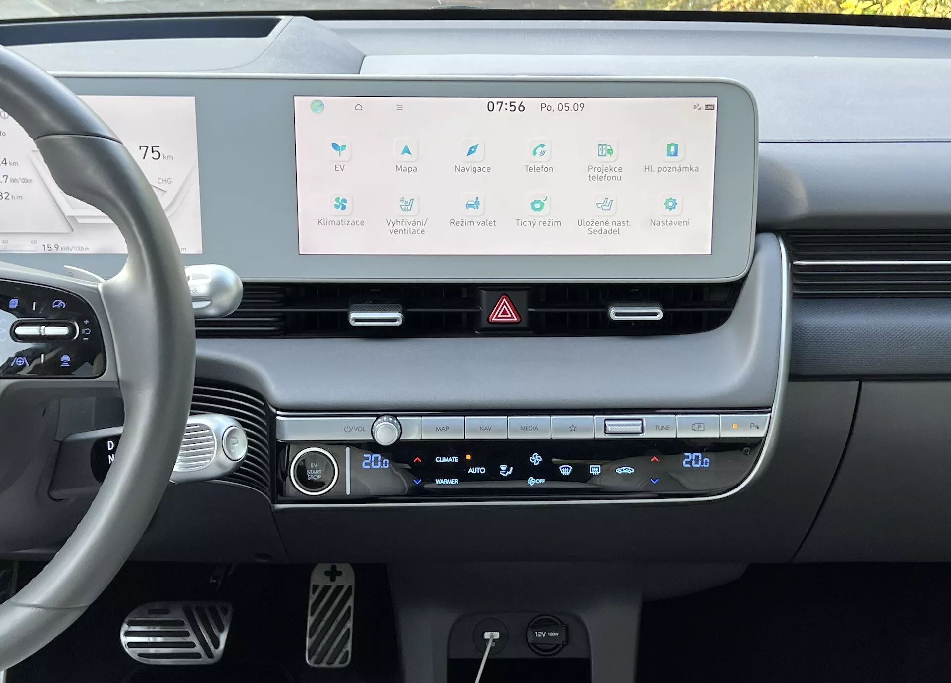 Interior do Hyundai Ioniq 5 2021 mostrando a perspectiva do condutor do painel de bordo com um grande ecrã táctil de infotainment, controlo de clima de duas zonas e controles modernos no volante, enfatizando a tecnologia avançada e o design minimalista do carro.