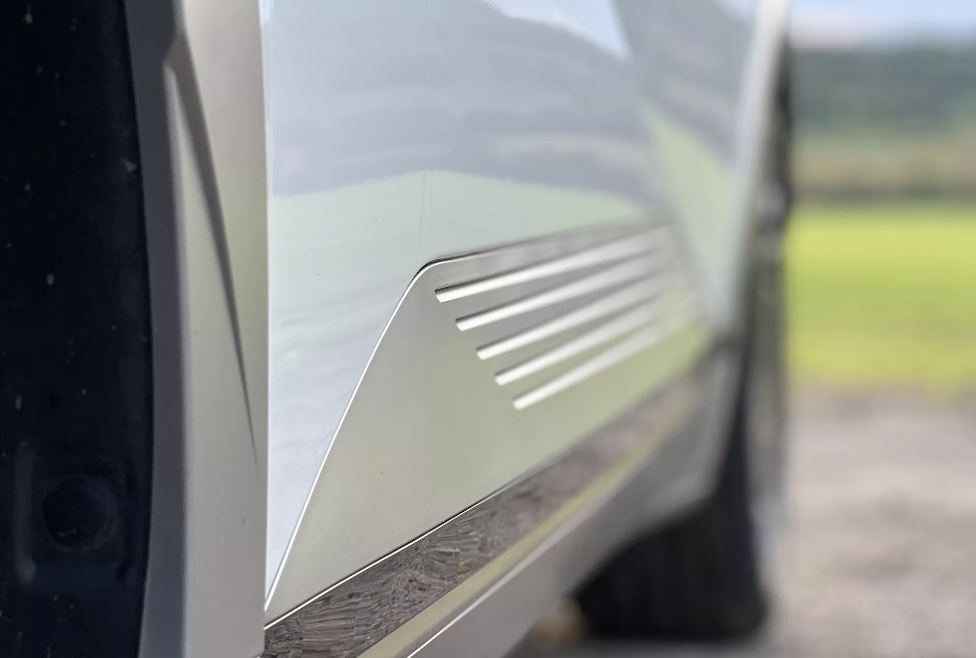 Vista detalhada de um Hyundai Ioniq-5 2021 focalizando no design detalhado da ventilação no painel traseiro lateral, pintado em uma cor clara e brilhante, enfatizando as características aerodinâmicas do veículo e a beleza estética.