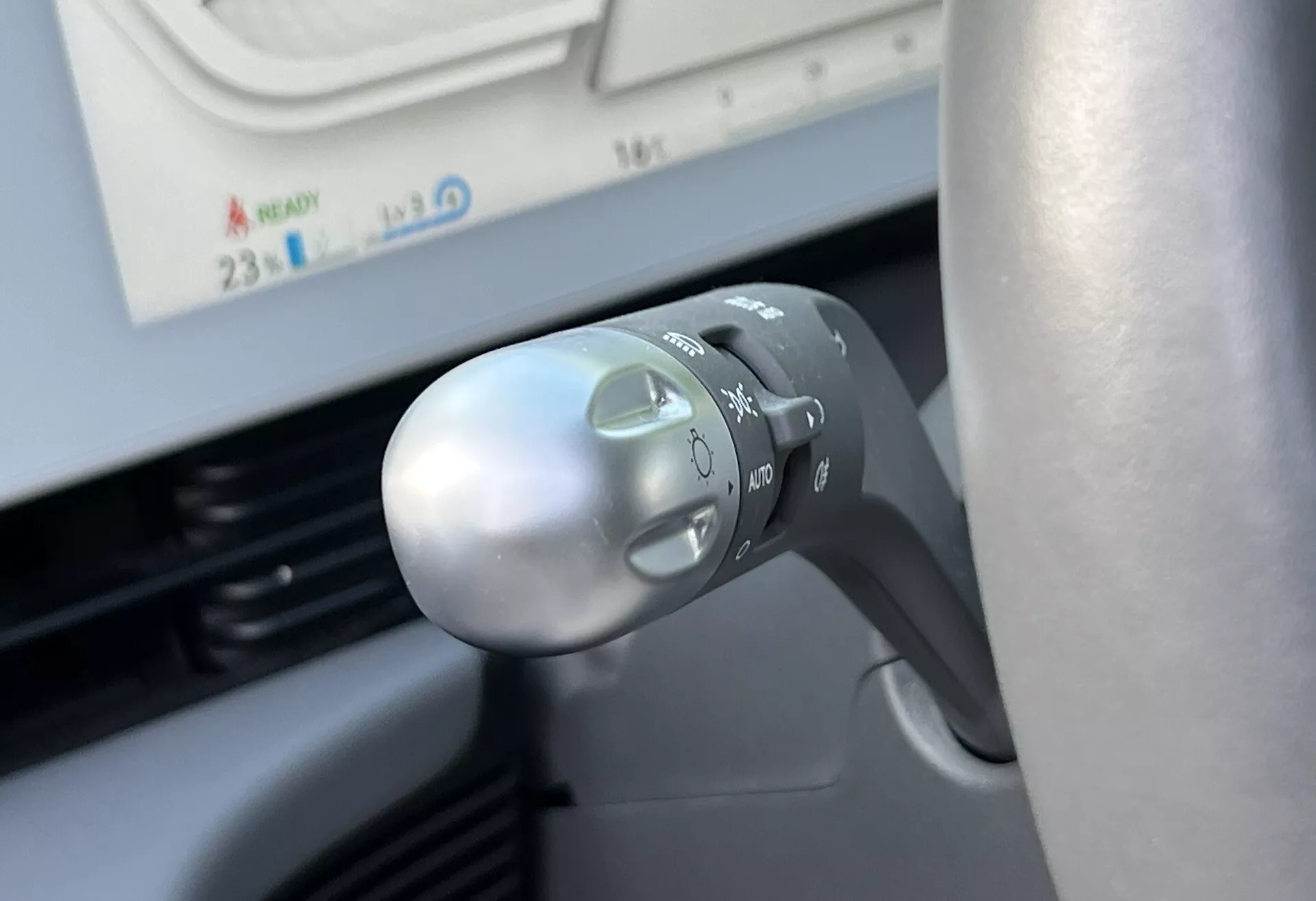 Visão detalhada da alavanca de sinalização e controle de luzes da Hyundai Ioniq-5 2021 na coluna de direção, mostrando símbolos para faróis, modo automático, sinais de mudança de direção e design ergonômico sob a perspectiva do motorista