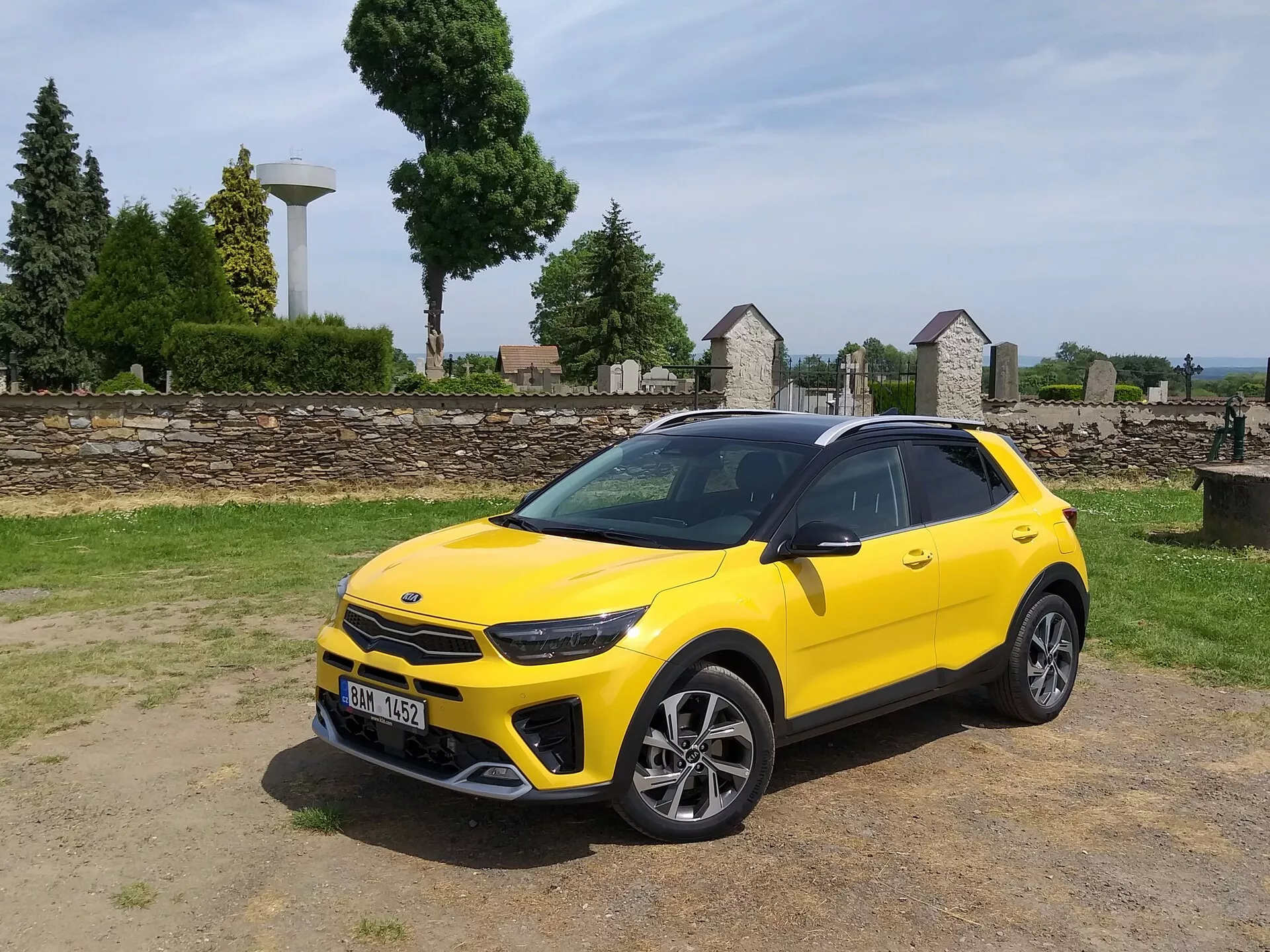 Kia Stonic 2017 em amarelo brilhante, apresentando sua grade frontal, faróis LED, para-choque dianteiro esportivo e perfil lateral elegante com rodas de liga leve multiraiadas e barras de teto, destacando a estética de crossover compacto e os recursos de design avançado do veículo.