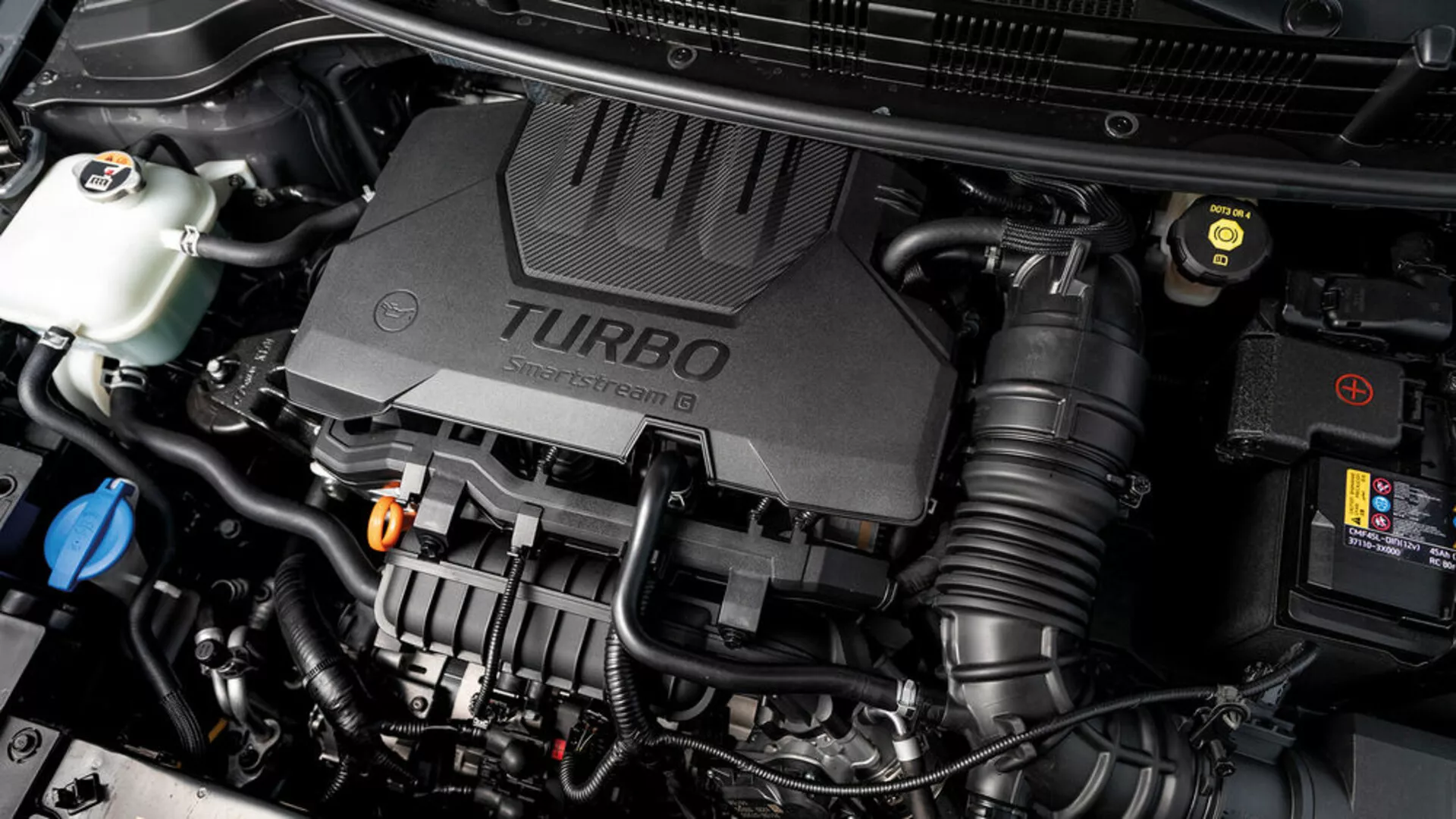 Vista detalhada do compartimento do motor do Kia Stonic 2017 com tampa do motor turboalimentado e vários componentes mecânicos visíveis, exibindo aspectos tecnológicos do veículo