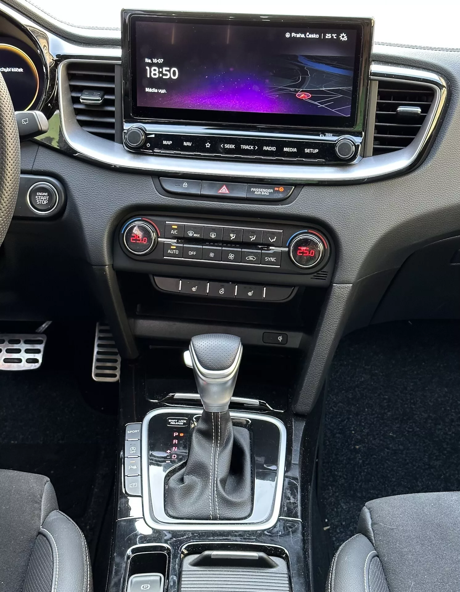 Vista interior do Kia Xceed 2022 mostrando o console central, painel de instrumentos, tela de infotenimento, botões de controle climático, alavanca de câmbio e áreas de armazenamento, destacando a tecnologia e design modernos do veículo.