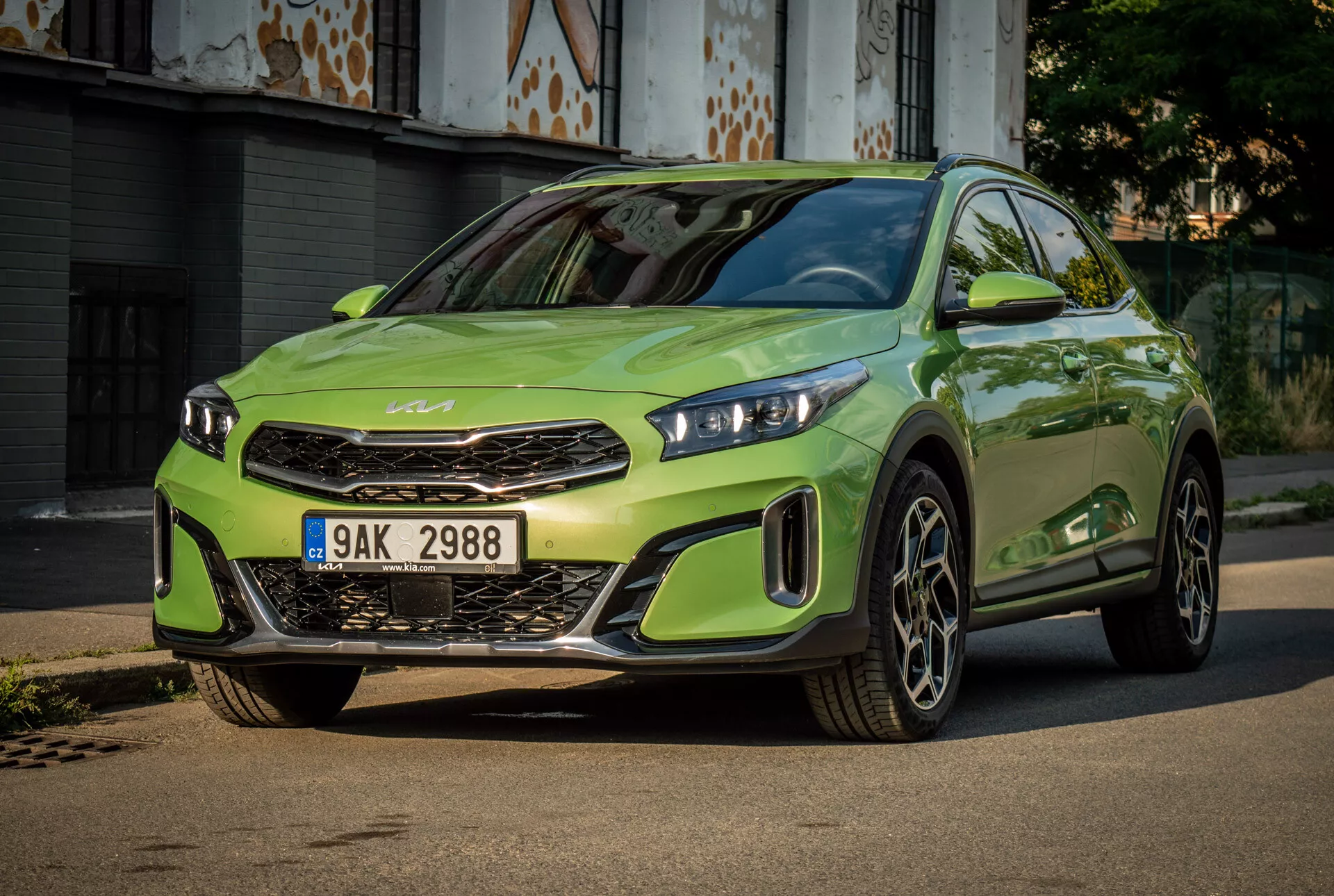 Kia XCeed 2022 em verde lima vibrante com faróis LED, grade frontal proeminente com emblema da marca, para-choque dianteiro esportivo e grandes rodas de liga leve, centralizado em uma estrada pavimentada com um fundo urbano