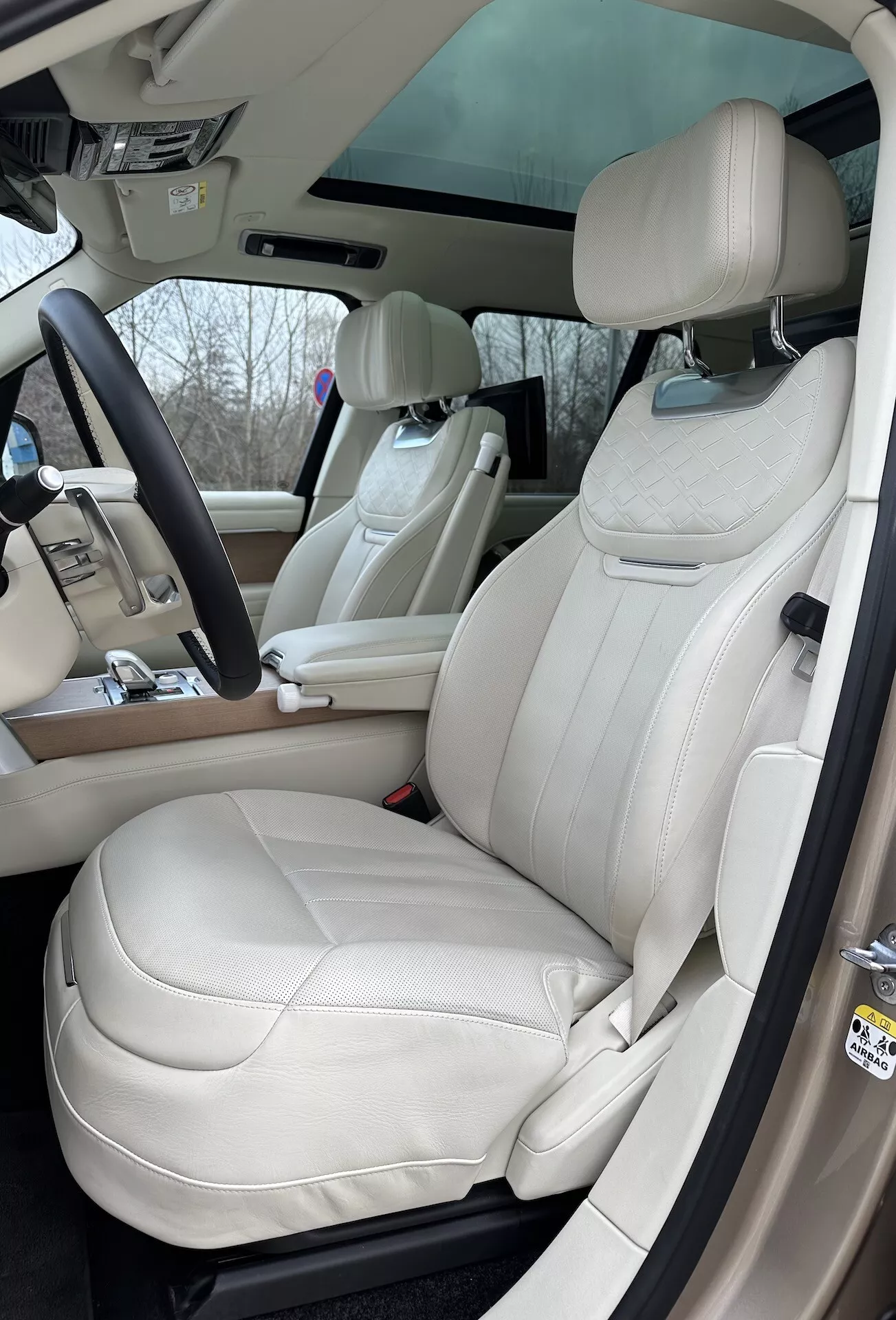 Vista interior do Land Rover Range Rover 2021 destacando o lado do motorista com assentos de couro creme de luxo, volante multifuncional e elementos de controle avançados no console central