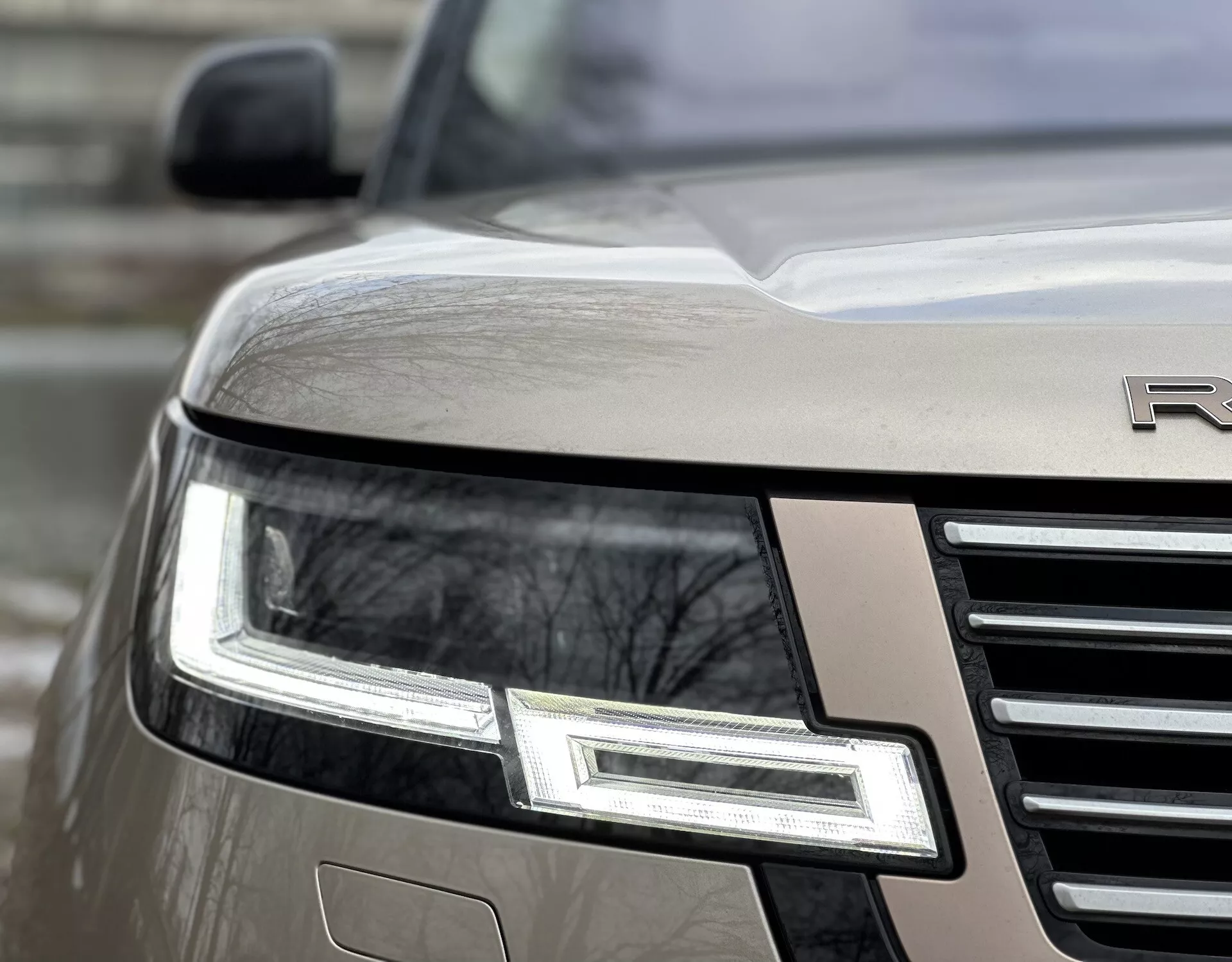 Visão angular e de perto do canto frontal do Land Rover Range Rover 2021 destacando o conjunto de farol LED, grade cromada e emblema parcial em um corpo metálico