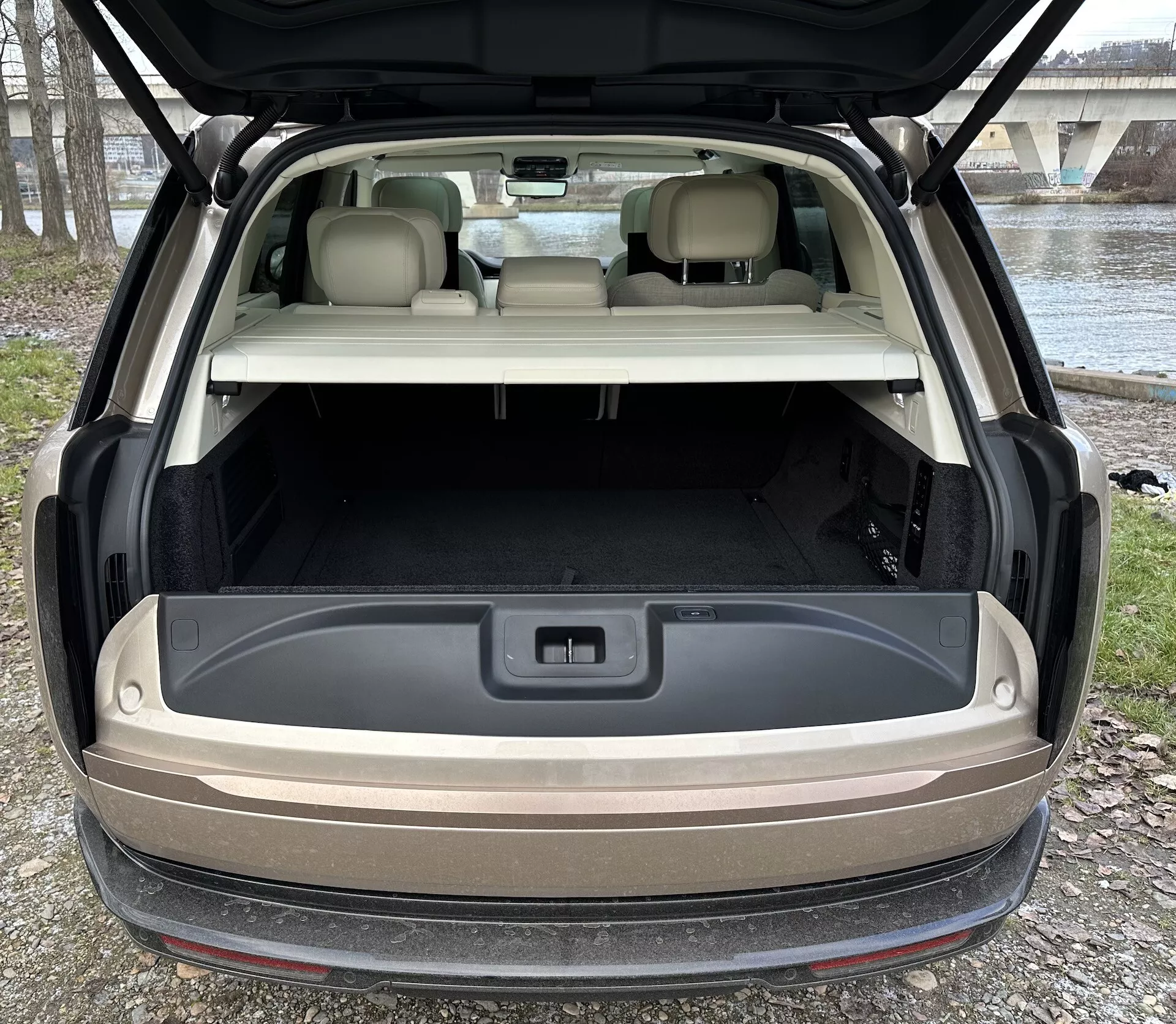 Vista traseira do Land Rover Range Rover 2021 com hatchback aberto mostrando área de carga espaçosa, iluminação avançada e tomada de 12 volts contra um cenário de luz natural ao ar livre