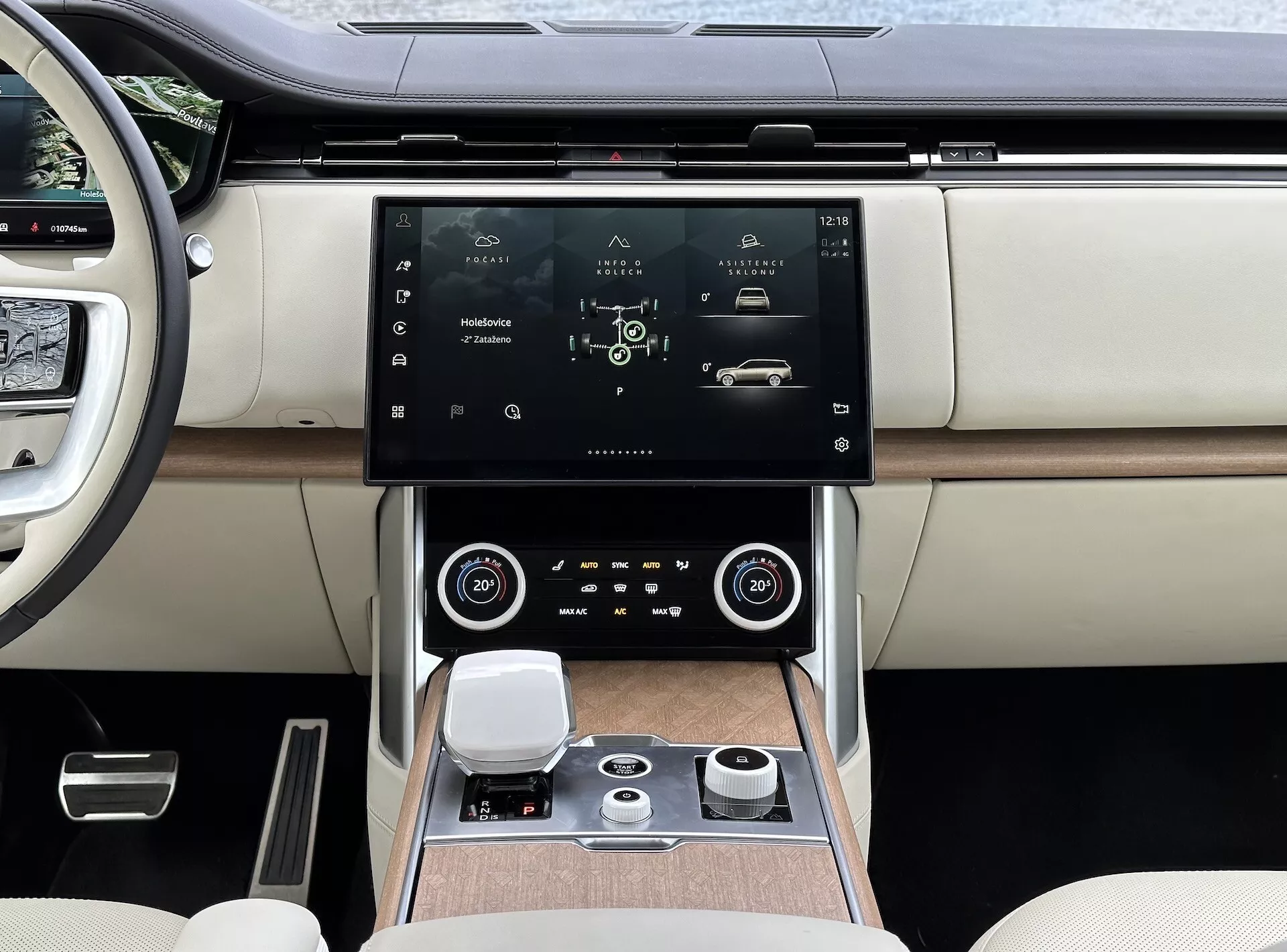 Land Rover Range Rover 2021 com interior moderno, focando no console central e sistema de infotainment com tela de toque de alta resolução, saídas de ar com detalhes em cromo, controle de clima de zona dupla, dial de controle giratório para navegação do sistema e assentos de luxo de couro em dois tons com detalhes de acabamento em madeira.
