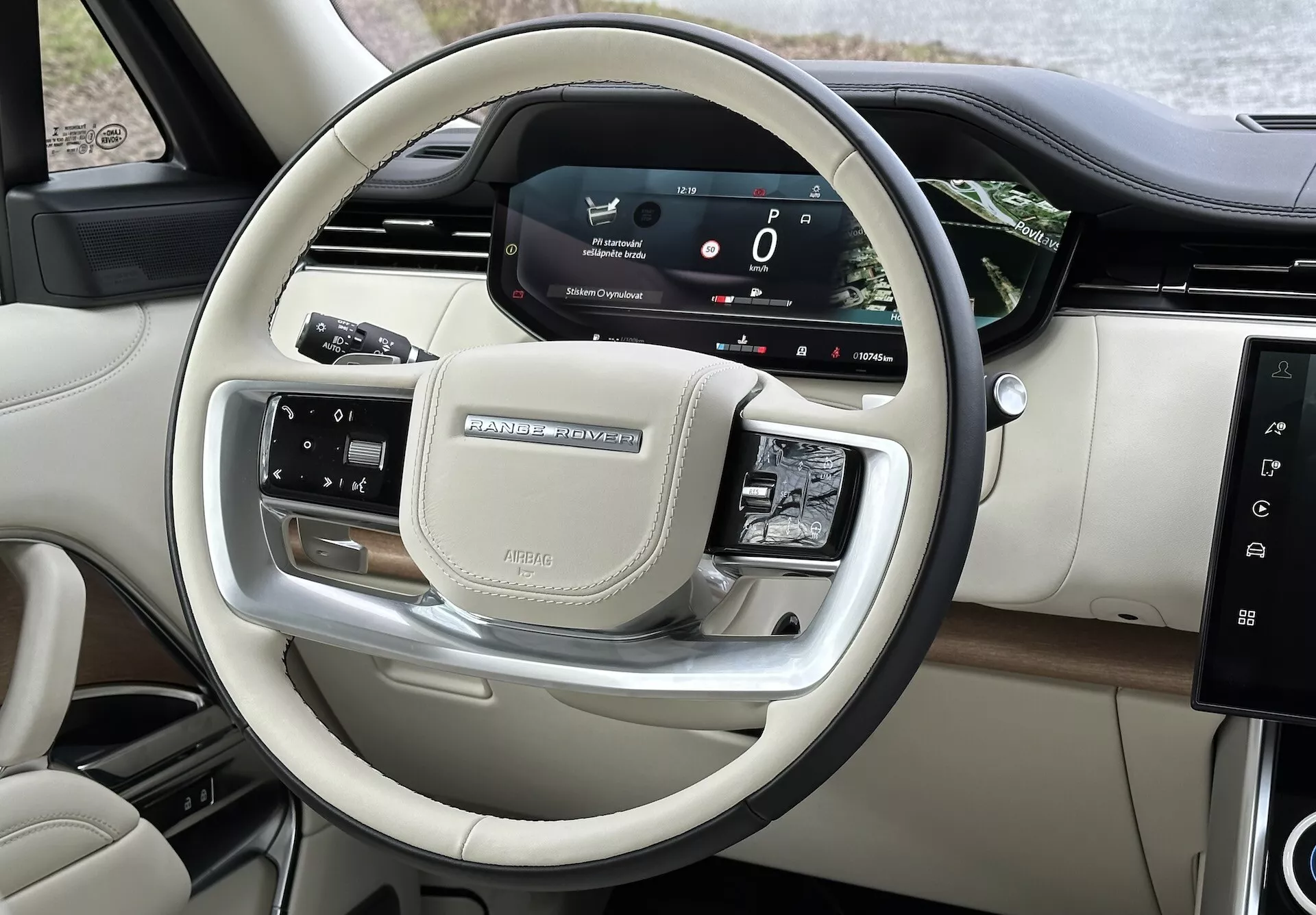 Vista interior do Land Rover Range Rover 2021 mostrando os controles no volante e o painel digital do motorista com acabamento cromado e de luxo
