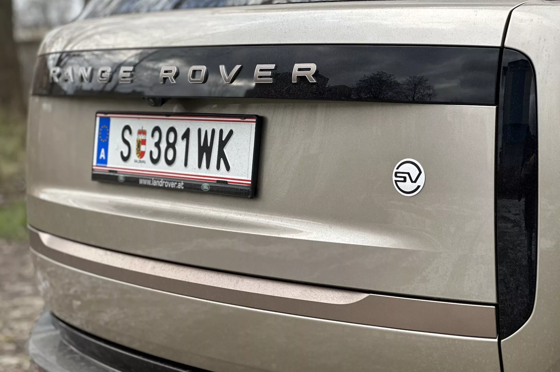 Vista detalhada da parte traseira de um Range Rover 2021 mostrando a marcação 'RANGE ROVER', placa no estilo europeu, emblema EV e parte da luz traseira