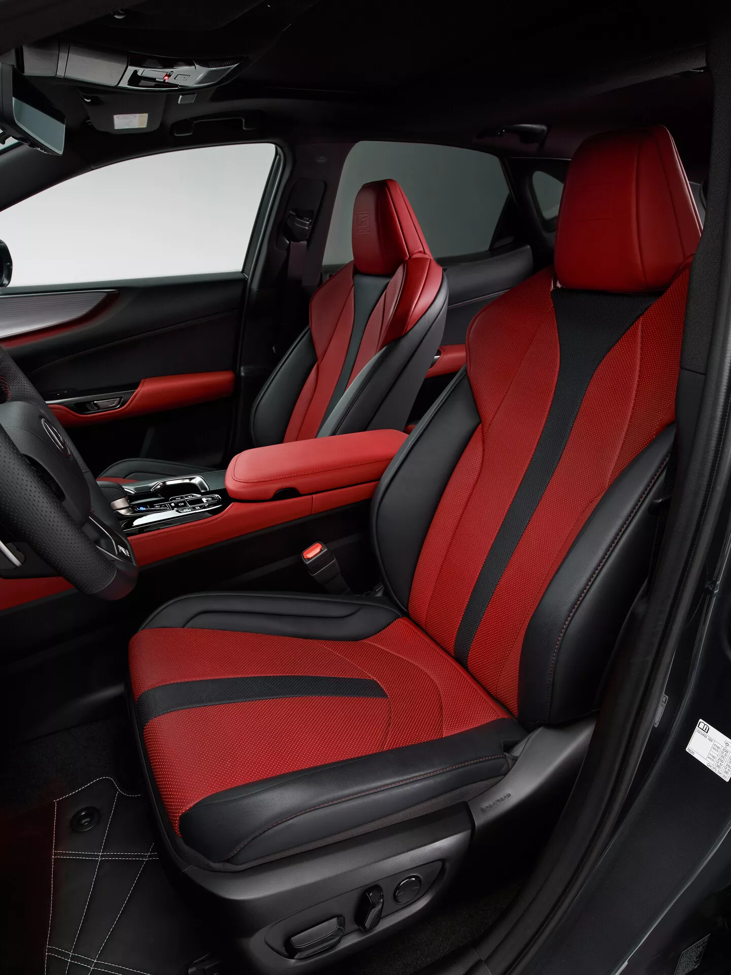 Foto do interior de um Lexus NX 2021 mostrando a área do passageiro dianteiro a partir do ângulo do lado do motorista. A imagem enfatiza o banco do passageiro com estofamento vermelho ousado e detalhes em preto, apresentando um design esportivo com reforço adicional e controles ajustáveis eletronicamente. O painel da porta combina com o esquema de cores preto e vermelho, com couro, tecido, um bolso de armazenamento, uma grade de alto-falante e vários controles. O console central ostenta uma alavanca de câmbio automática e um apoio de braço central com costura vermelha, refletindo o design luxuoso e esportivo do veículo.
