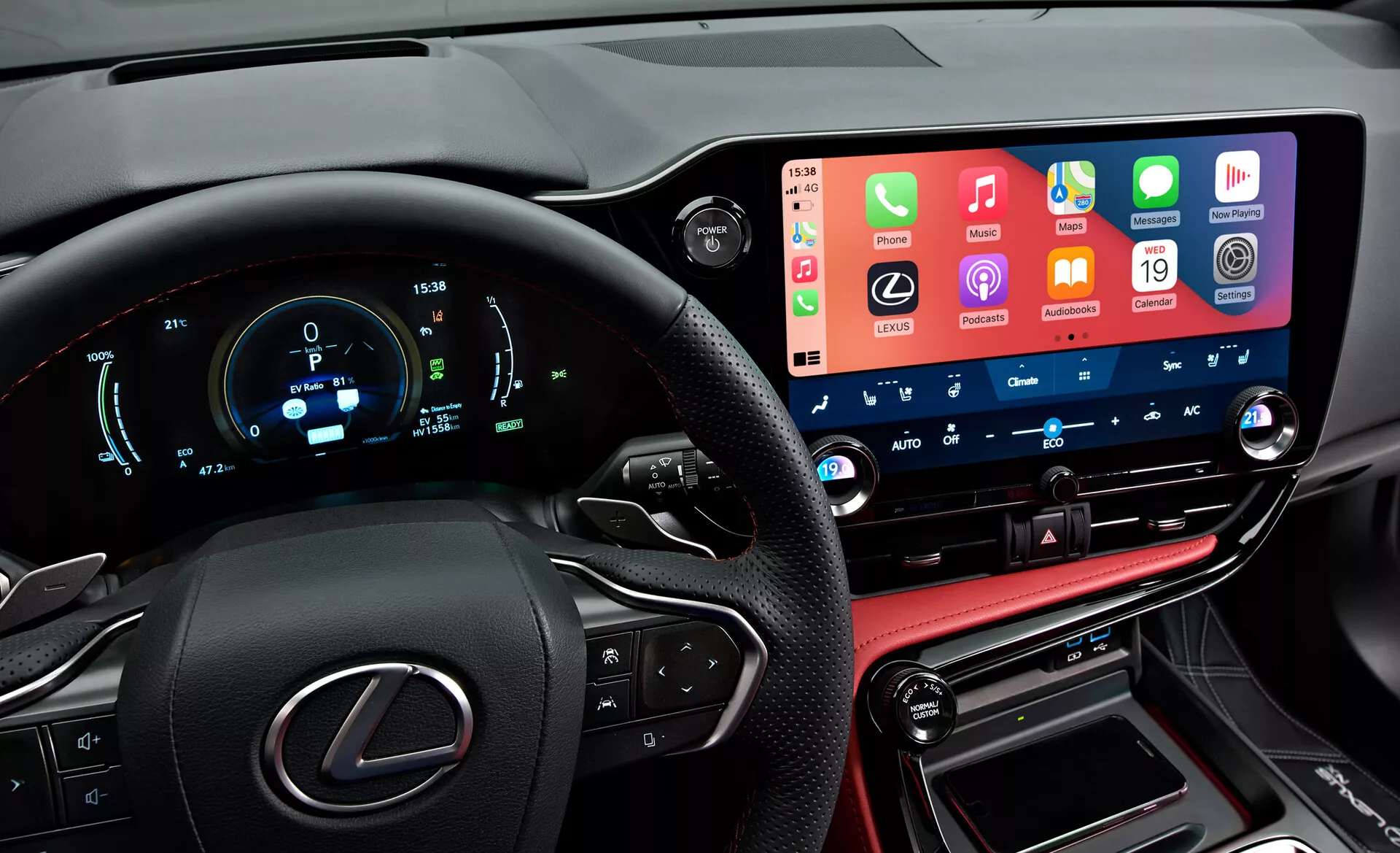 Visão interna de um Lexus NX 2021 mostrando um painel de instrumentos moderno e de alta tecnologia da perspectiva do motorista. À esquerda, vê-se parcialmente o volante com o logotipo da Lexus e botões multifuncionais. O painel de instrumentos digital exibe velocidade, rpm e outras métricas em azul e branco. No centro, o sistema de infoentretenimento com tela sensível ao toque ampla e proeminente integra funcionalidades de smartphones. Abaixo estão os botões e mostradores de controle de clima com displays digitais de temperatura. A seção inferior inclui um console com costura em couro, a alavanca de câmbio e portas de conectividade, refletindo o acabamento luxuoso do veículo.