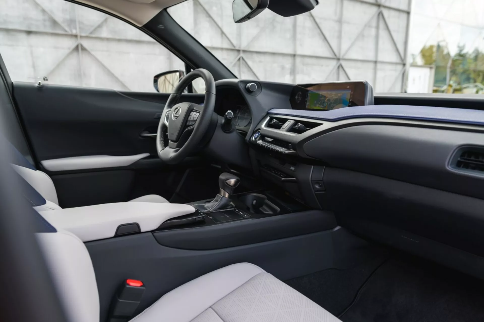 Interior moderno do Lexus UX 2019 mostrando um design em dois tons, volante multifunções, tela de infotainment proeminente e transmissão automática de um ângulo ligeiramente descentralizado, ao nível dos olhos