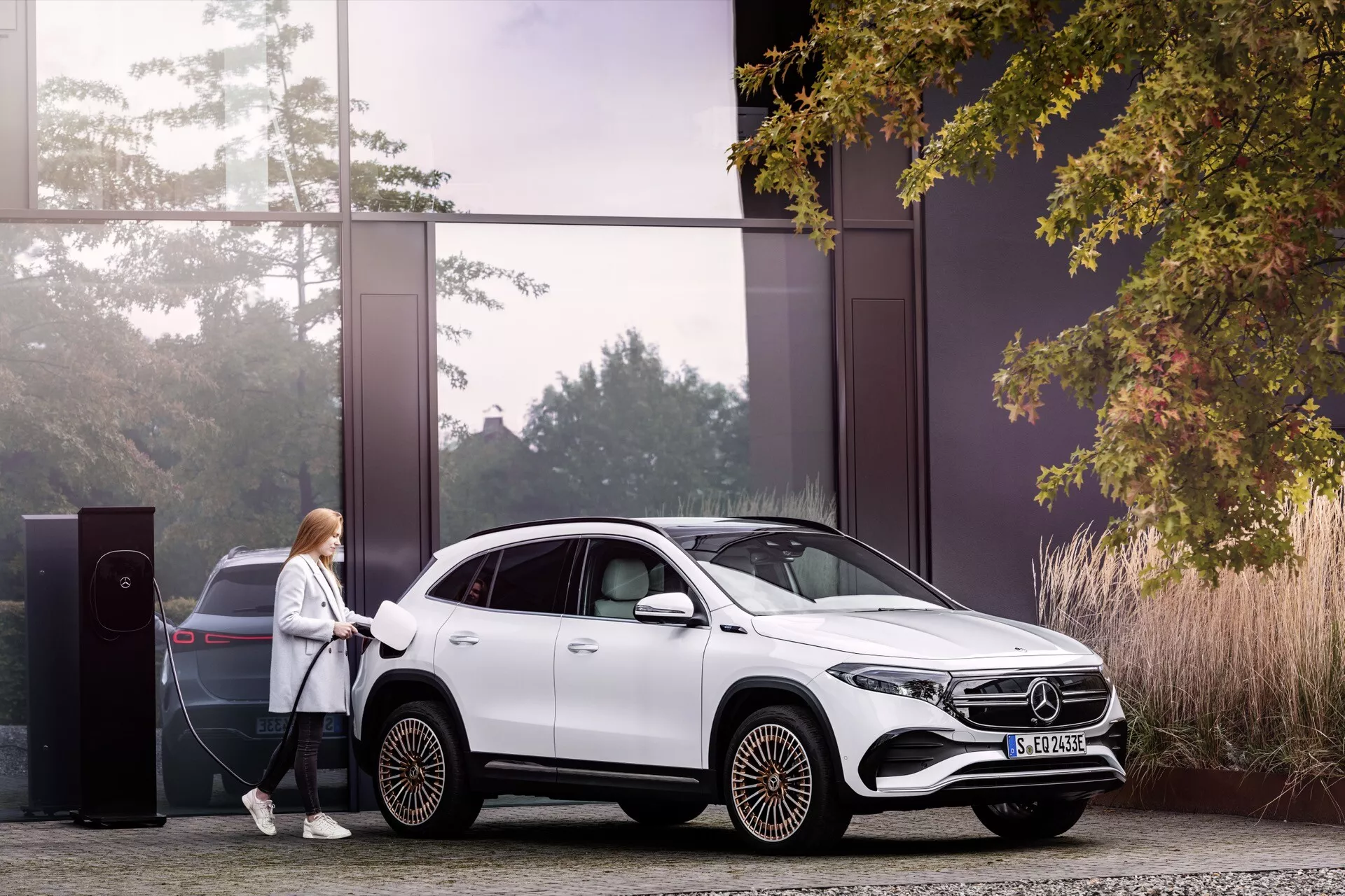 Mercedes-Benz EQA 2021 estacionado em uma estação de carregamento elétrico, exibindo seu design elegante branco, padrão de roda aerodinâmica e capacidades híbridas em um ambiente sustentável