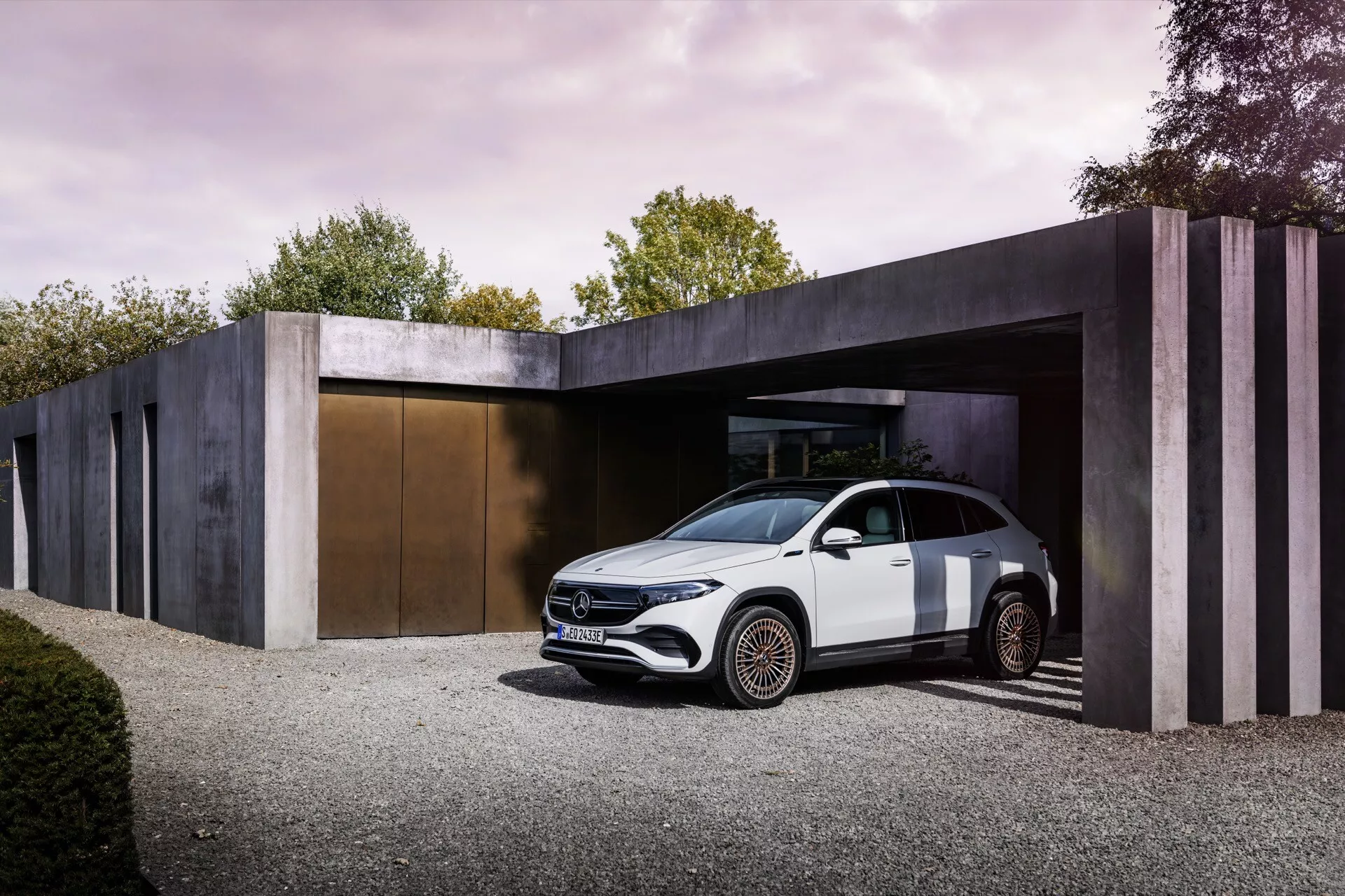 Mercedes-Benz EQA 2021 estacionado na entrada de um edifício de estilo minimalista exibindo sua vista frontal de três quartos sob luz diurna suave, destacando seu design aerodinâmico elegante, faróis LED, linha de ombro alta, silhueta tipo coupé, maçanetas embutidas, rodas de liga leve de design intricado e potencial para sistemas avançados de assistência ao condutor.