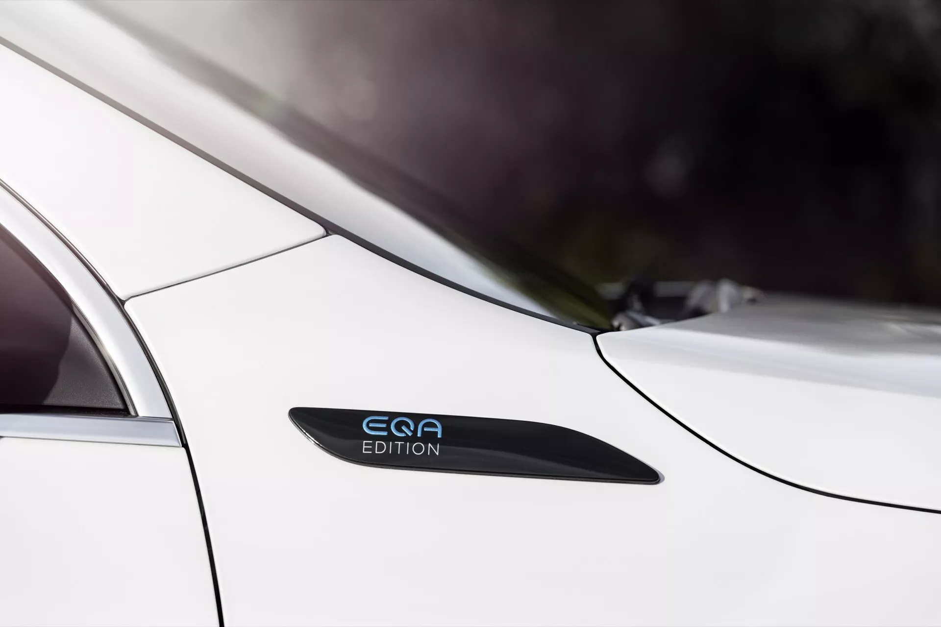 Close-up do Mercedes-Benz EQA 2021 mostrando o perfil lateral elegante perto da porta do passageiro traseiro e para-lama traseiro, destacando a pintura branca, insígnia 'EQE EDITION', design de porta sem maçaneta e linhas de design sugerindo estética moderna e tecnologia avançada.