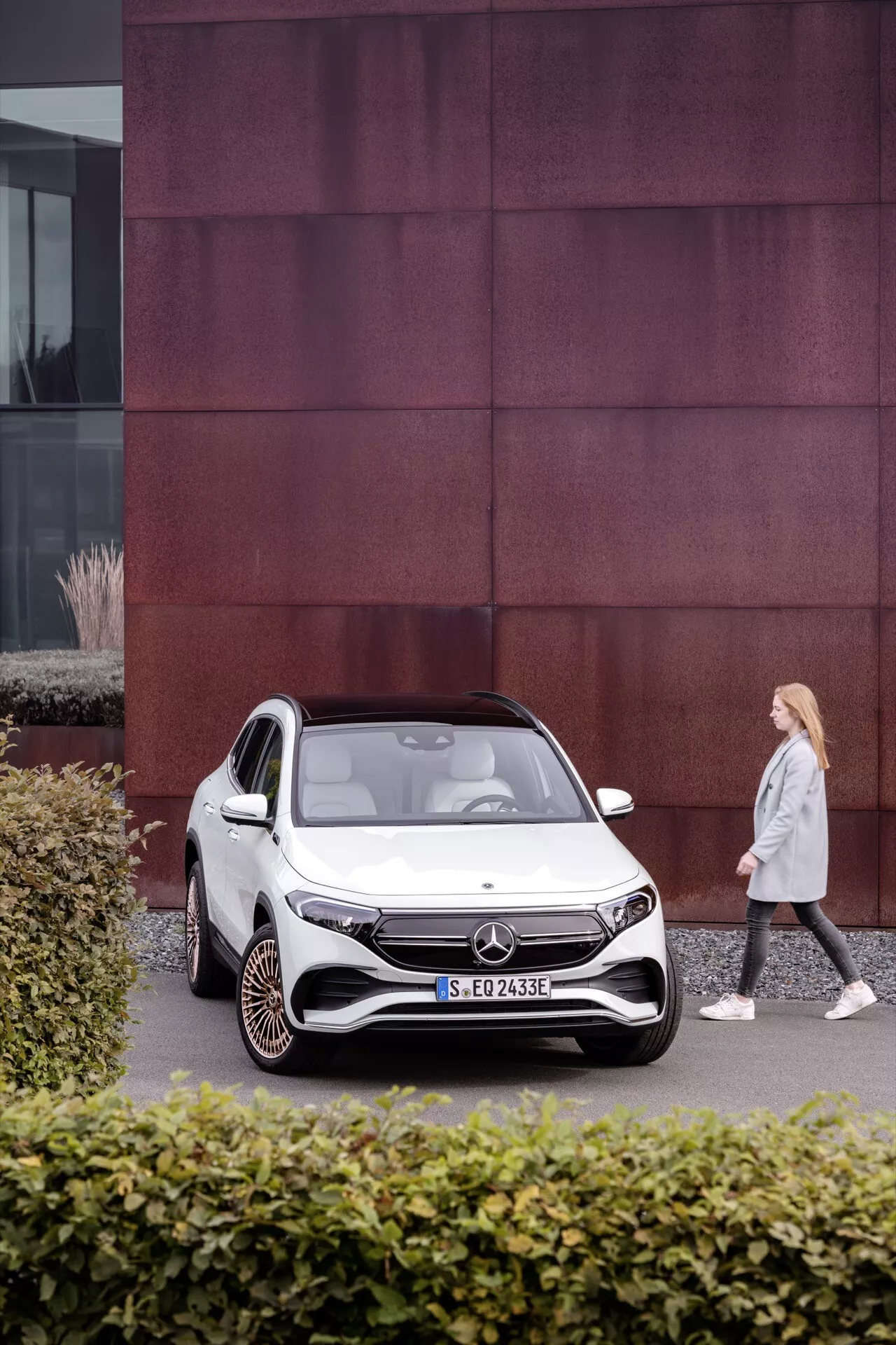Mercedes-Benz EQA 250 de 2021 estacionado em ambiente urbano com fachada de edifício distintiva de painéis vermelhos, exibindo design de SUV compacto elétrico e recursos avançados como faróis LED e rodas aerodinâmicas
