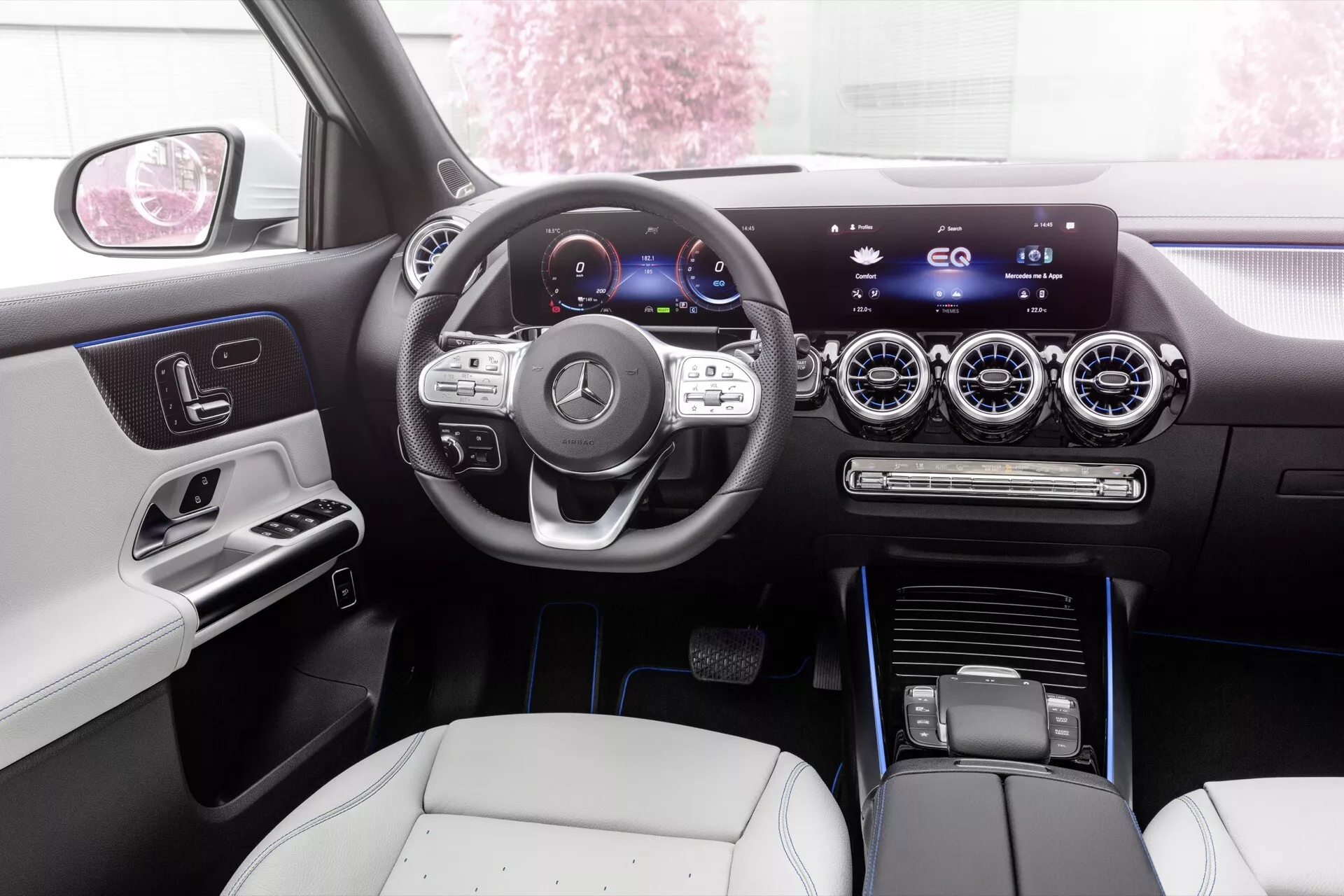 Vista interior do Mercedes-Benz EQA 2021 mostrando o painel elegante, cluster de instrumentos digital, volante multifuncional e sistema de infotenimento central touchscreen a partir da perspectiva do banco traseiro