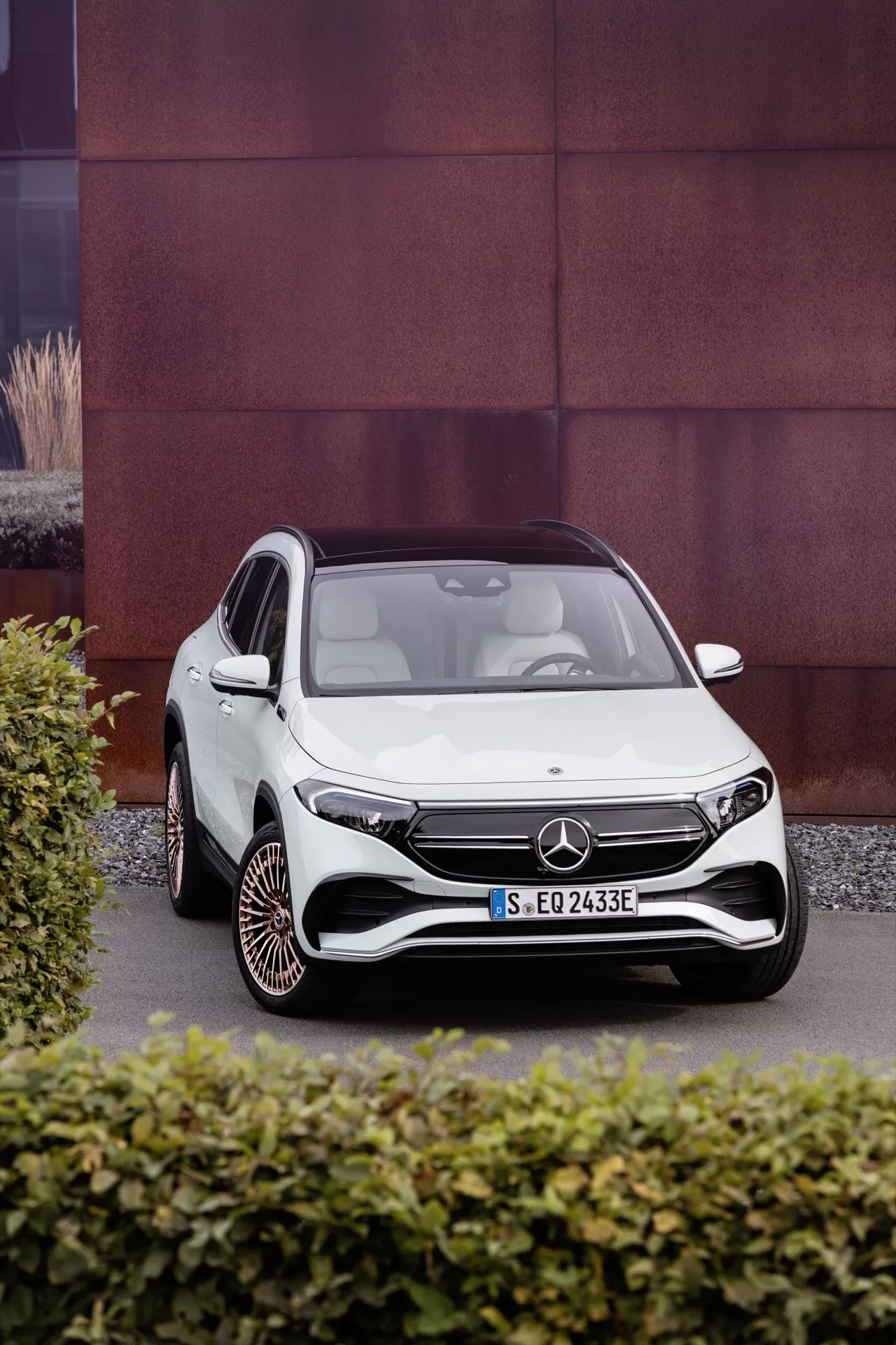 Mercedes-Benz EQA 2021 em branco, fotografado de um ângulo frontal de três quartos destacando o design aerodinâmico do veículo, faróis LED, grade frontal distinta com um grande emblema, para-choque dianteiro esportivo e design único das rodas em um fundo texturizado contrastante