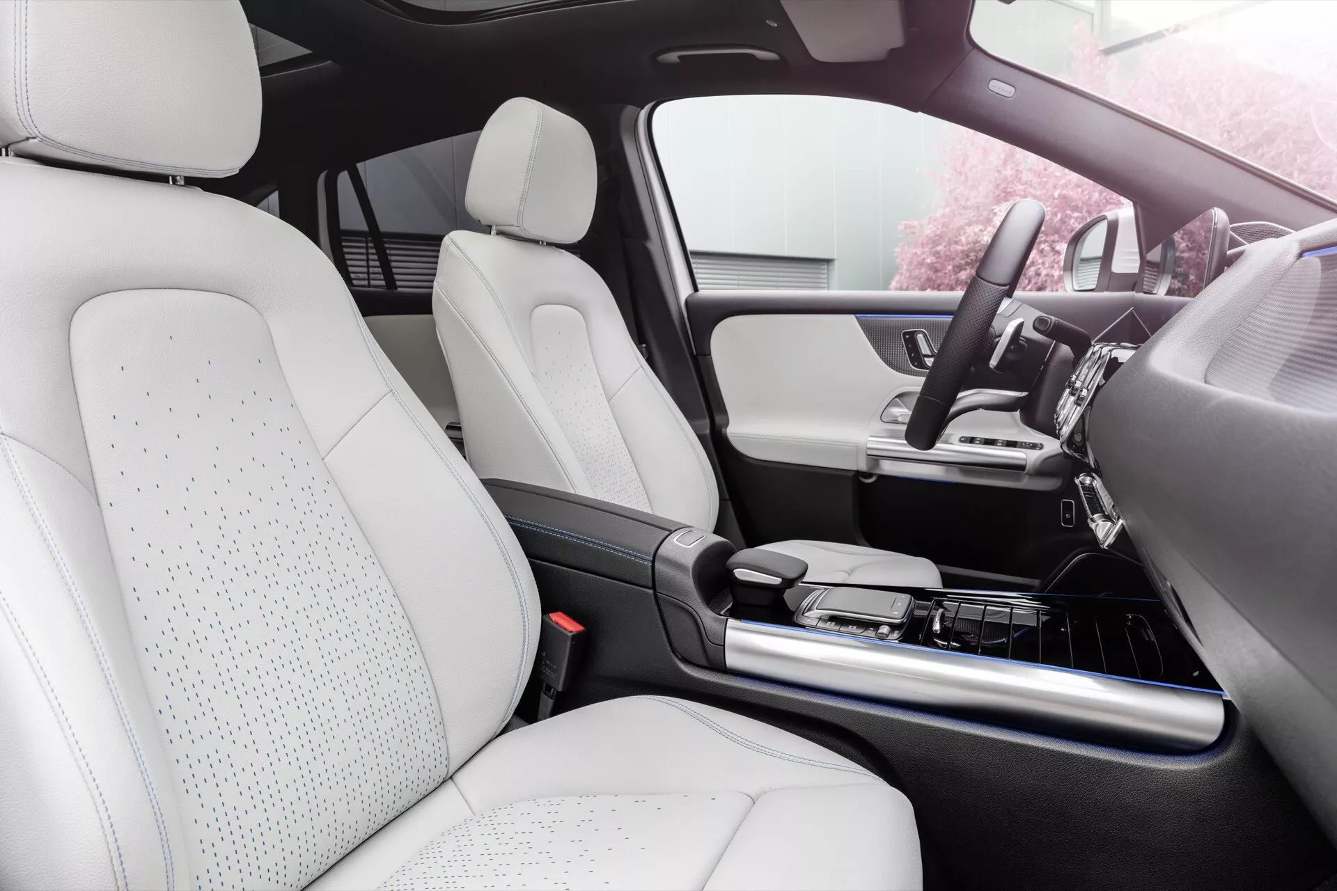 Vista do interior de um Mercedes-Benz EQA 2021 destacando a área do assento do passageiro, o painel frontal, console central e os assentos em couro branco perfurado sugerindo a tecnologia de assentos ventilados para conforto adicional, integrado com um sistema de infotenimento avançado e elementos de design de luxo.