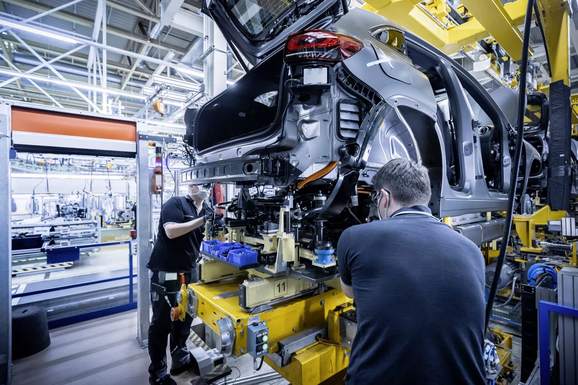 Mercedes-Benz EQA 2021 (243) em meio montagem mostrando o quarto traseiro esquerdo com interiores expostos e suspensão, em uma instalação de fabricação de automóveis moderna