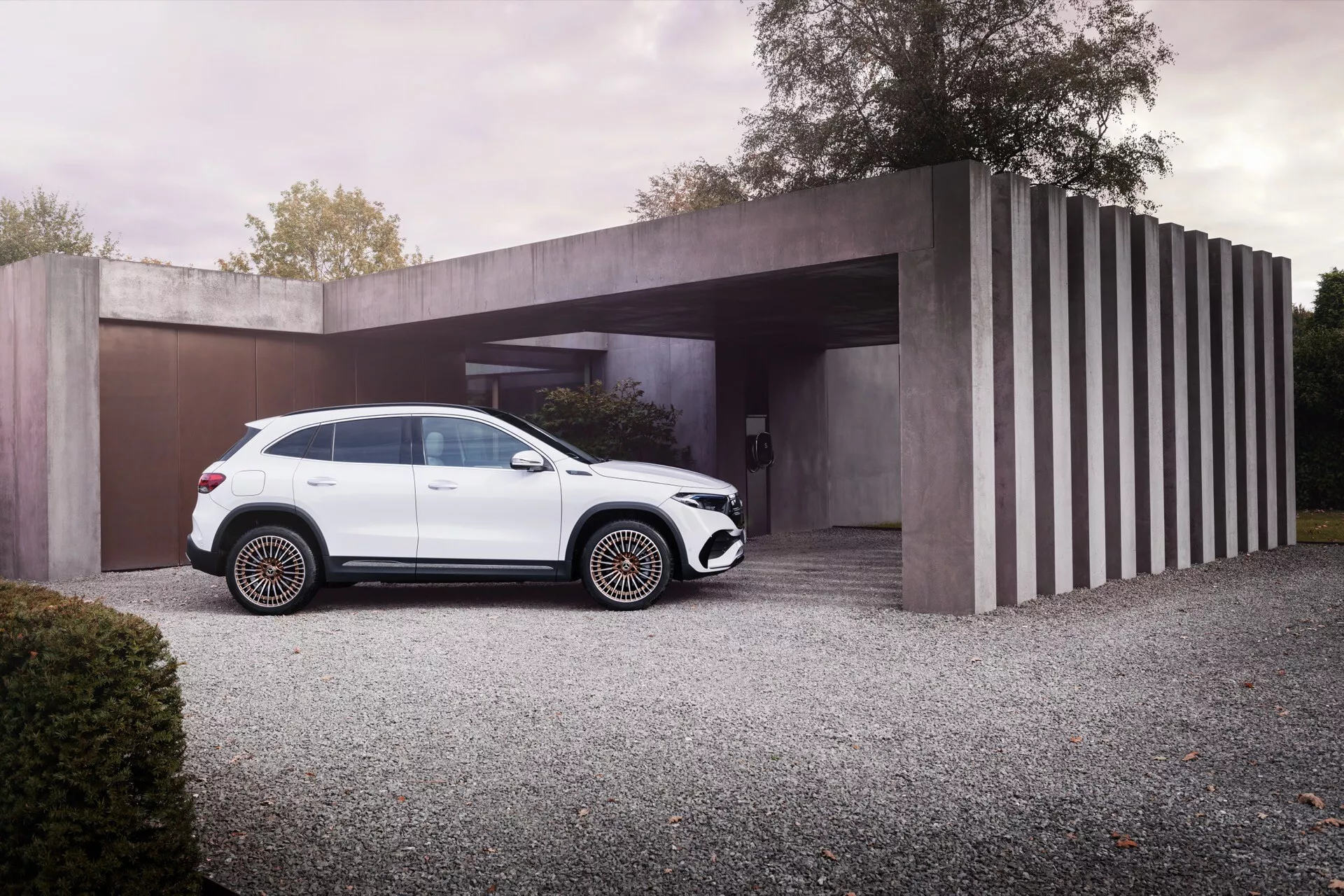 SUV de luxo Mercedes-Benz EQA 2021 branco estacionado em uma entrada de cascalho com casa moderna minimalista ao fundo, exibindo design elegante, características em preto, rodas multi-raios e trilhos de teto