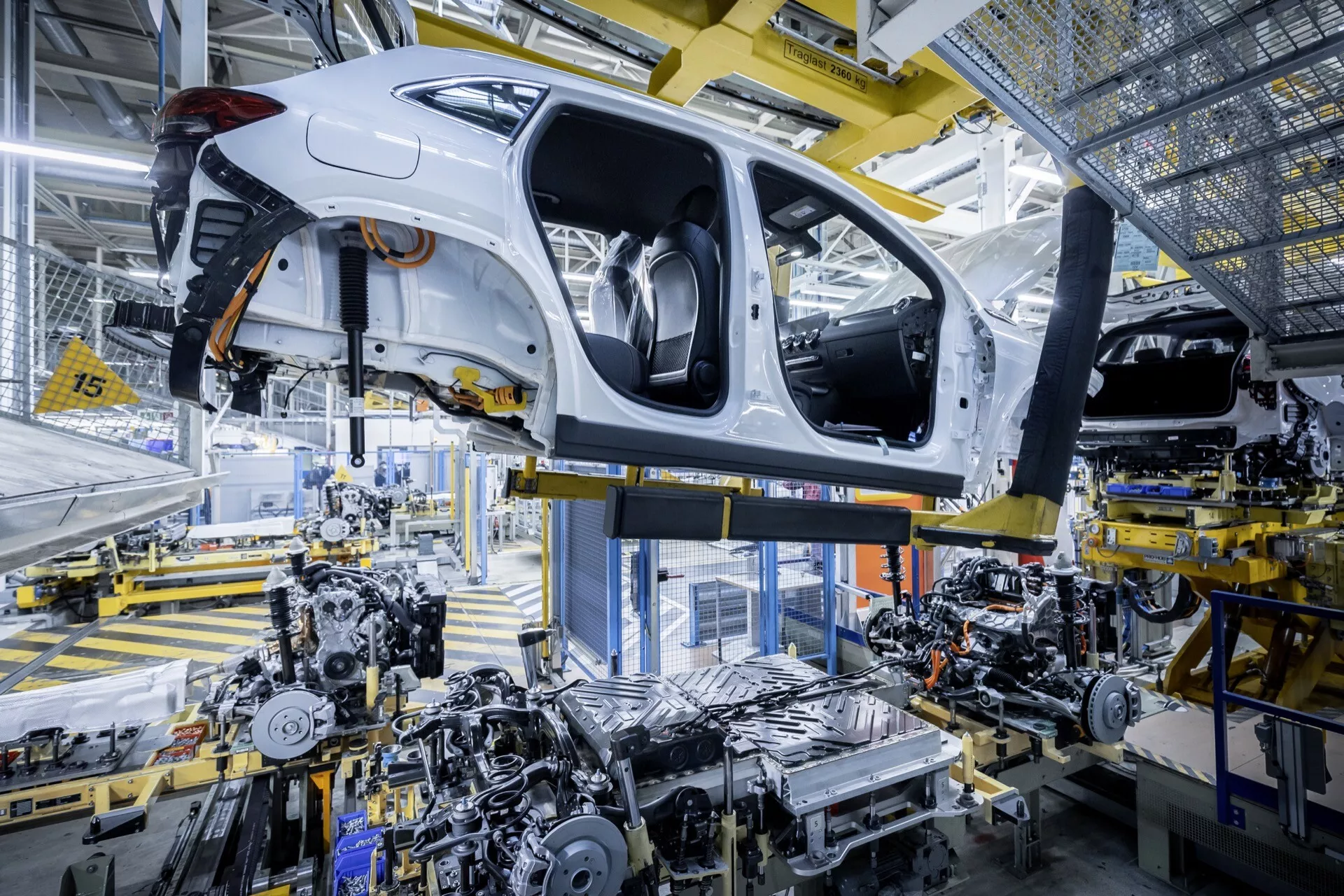 Mercedes-Benz EQA (243) branco de 2021, em processo de montagem em uma planta automotiva, mostrando seu chassi, parte inferior e tecnologia avançada de montagem robótica
