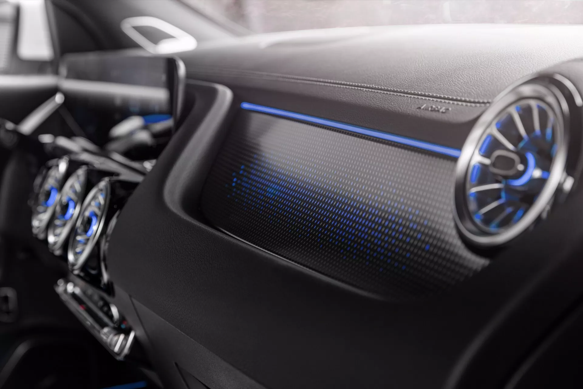 Close-up do interior do Mercedes-Benz EQA 2021 mostrando o painel do lado do passageiro com ventilação aérea metálica circular e iluminação ambiente azul fria, destacando design de luxo e características tecnológicas avançadas