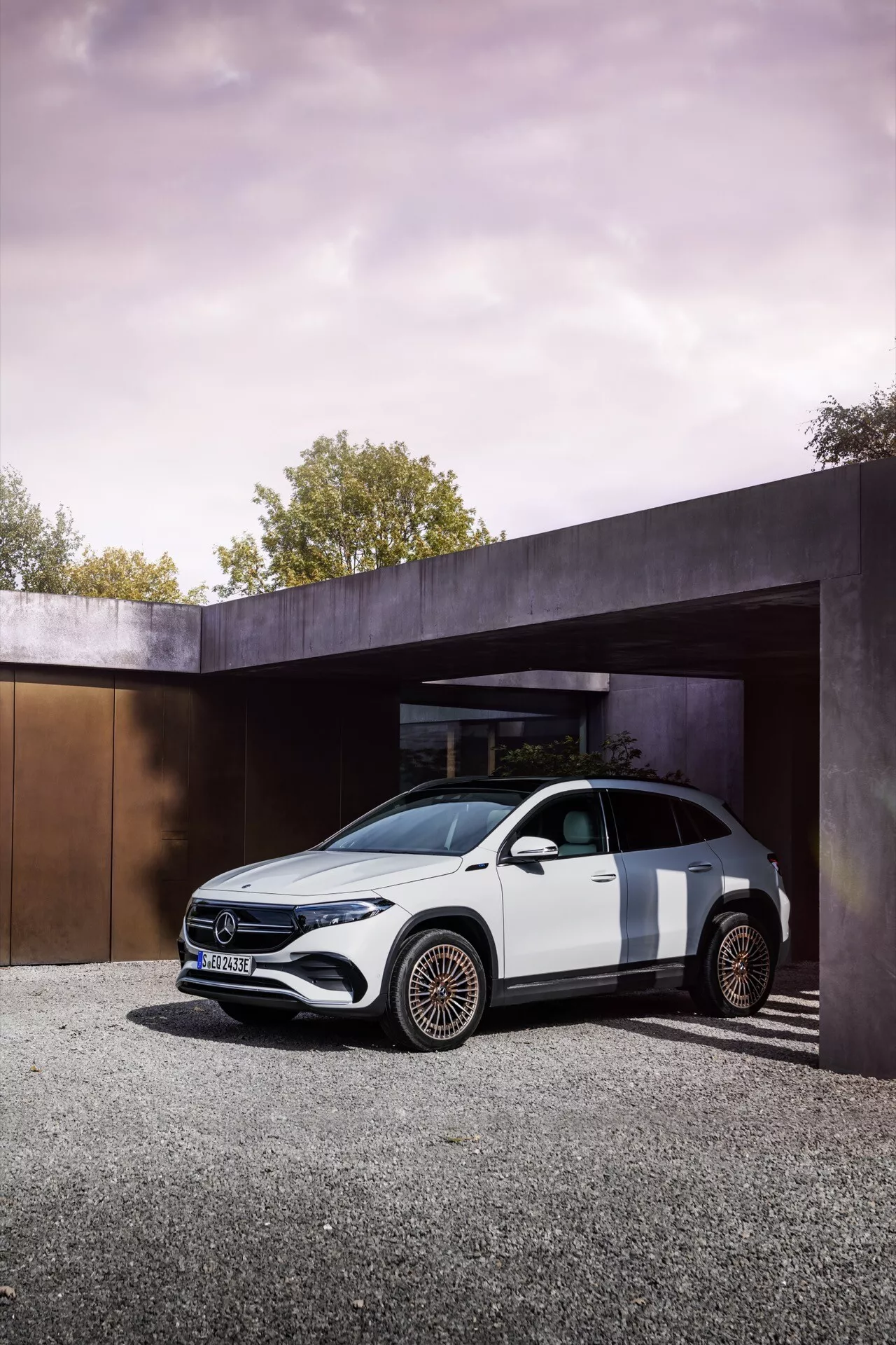Mercedes-Benz EQA 2021 estacionado sob estrutura arquitetônica moderna no início da manhã ou final da tarde exibindo elementos de design de luxo como grade frontal preta brilhante, faróis LED e rodas únicas de bronze