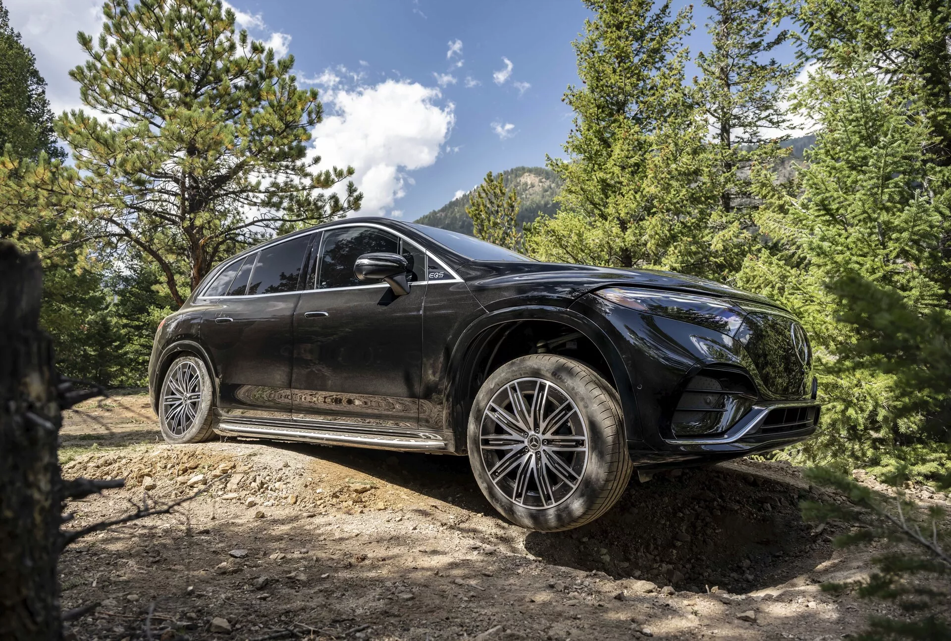 Vista frontal de três quartos do Mercedes EQS SUV 2022, exibindo seu design elegante, faróis LED avançados, teto solar panorâmico e rodas de liga premium em um ambiente urbano sofisticado.