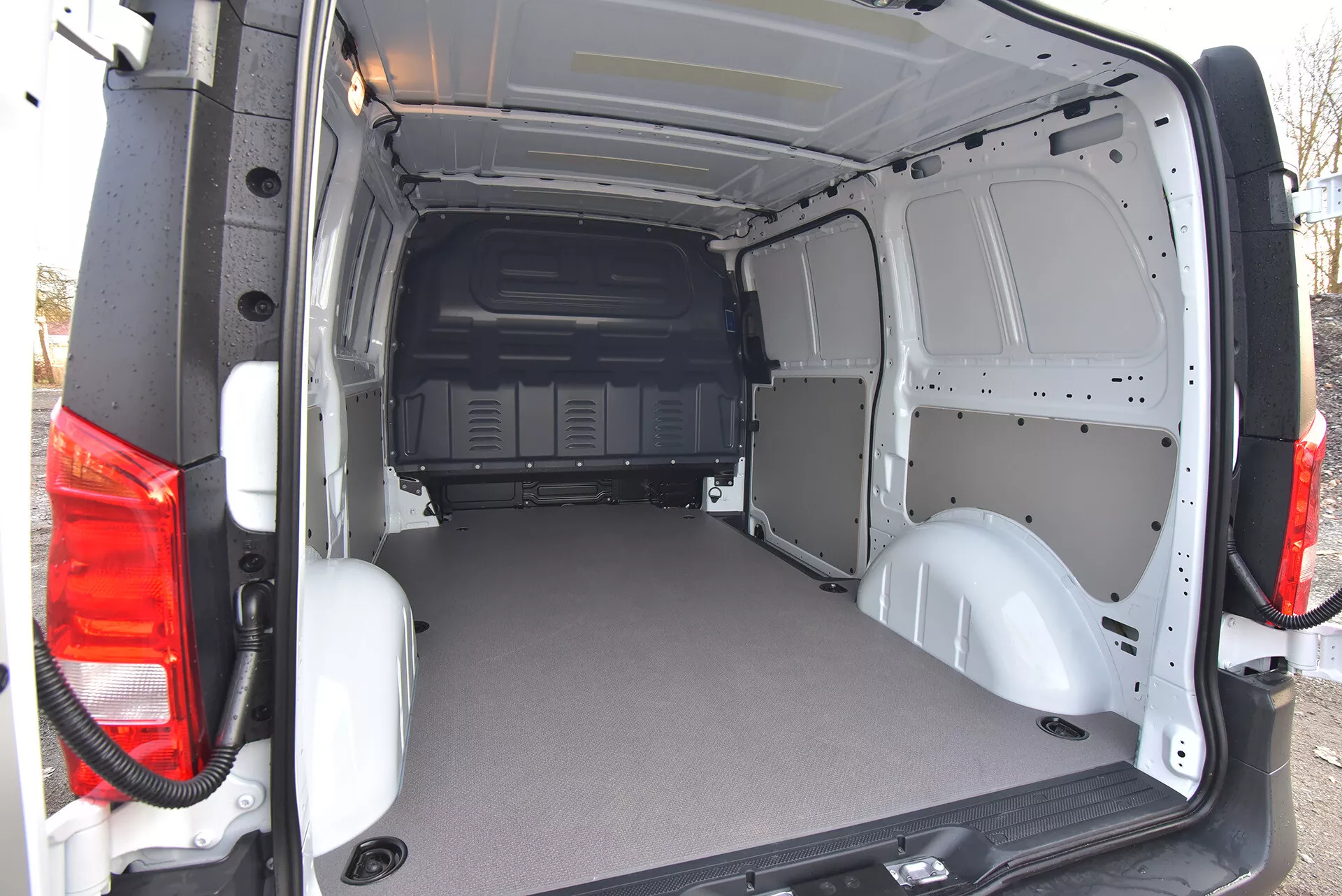 Área de carga traseira da van comercial Mercedes-Benz Vito Tourer 2014 com portas abertas exibindo piso durável e plano e interior em metal exposto para facilidade de personalização, visto de um ângulo exterior traseiro oblíquo